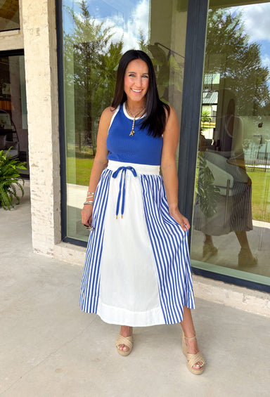 Sporty meets polished in this sleeveless midi dress by Entro—an effortless spring staple you’ll love wearing on repeat. The royal blue top features crisp white trim along the neckline and arm openings, while the white skirt is accented with royal blue and white stripe detailing along the sides for a clean, flattering look. An elastic tie waist adds comfort and shape, and side pockets make it as practical as it is cute. Fully lined and made from breathable cotton, this dress is perfect for all season long.