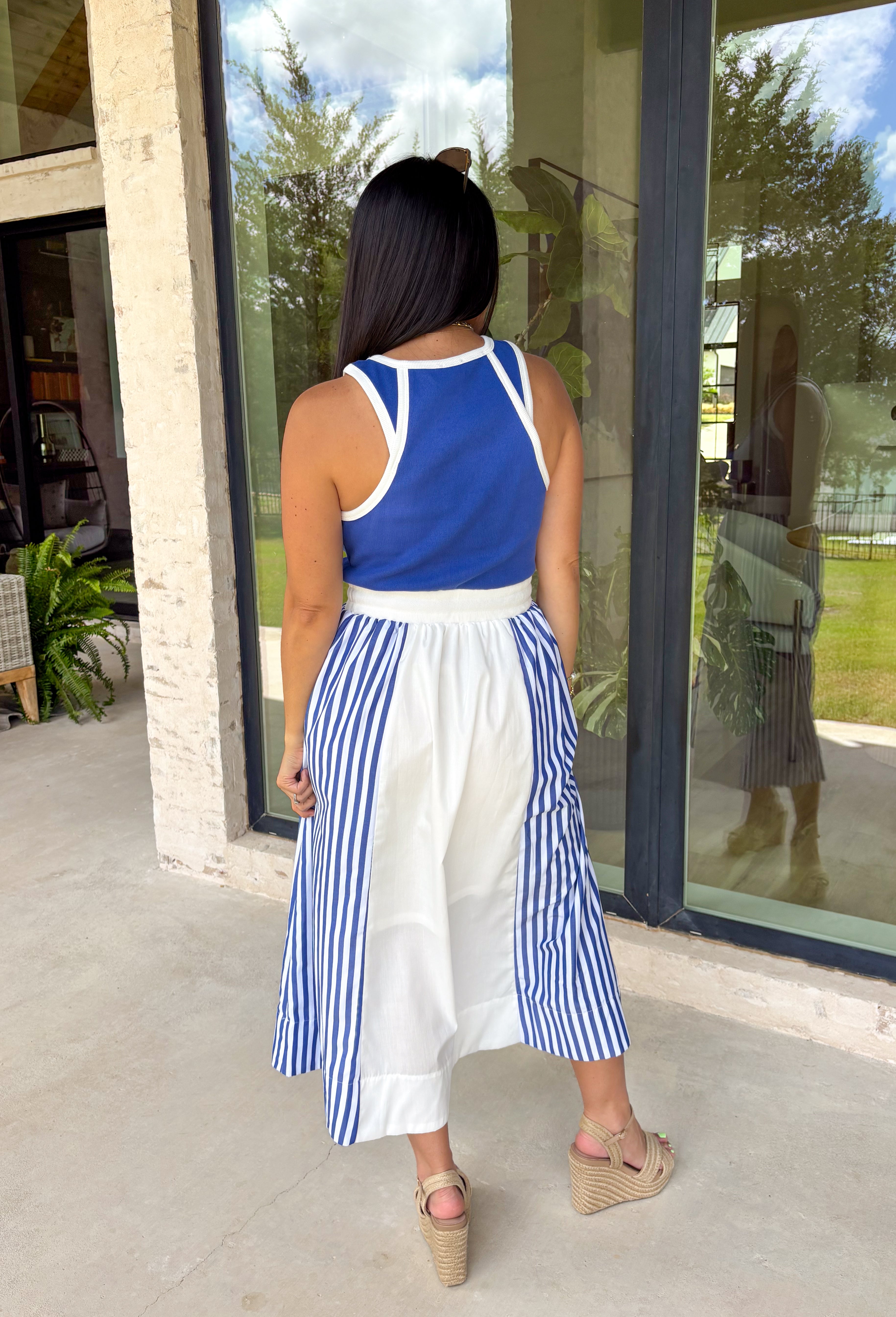 Sporty meets polished in this sleeveless midi dress by Entro—an effortless spring staple you’ll love wearing on repeat. The royal blue top features crisp white trim along the neckline and arm openings, while the white skirt is accented with royal blue and white stripe detailing along the sides for a clean, flattering look. An elastic tie waist adds comfort and shape, and side pockets make it as practical as it is cute. Fully lined and made from breathable cotton, this dress is perfect for all season long.