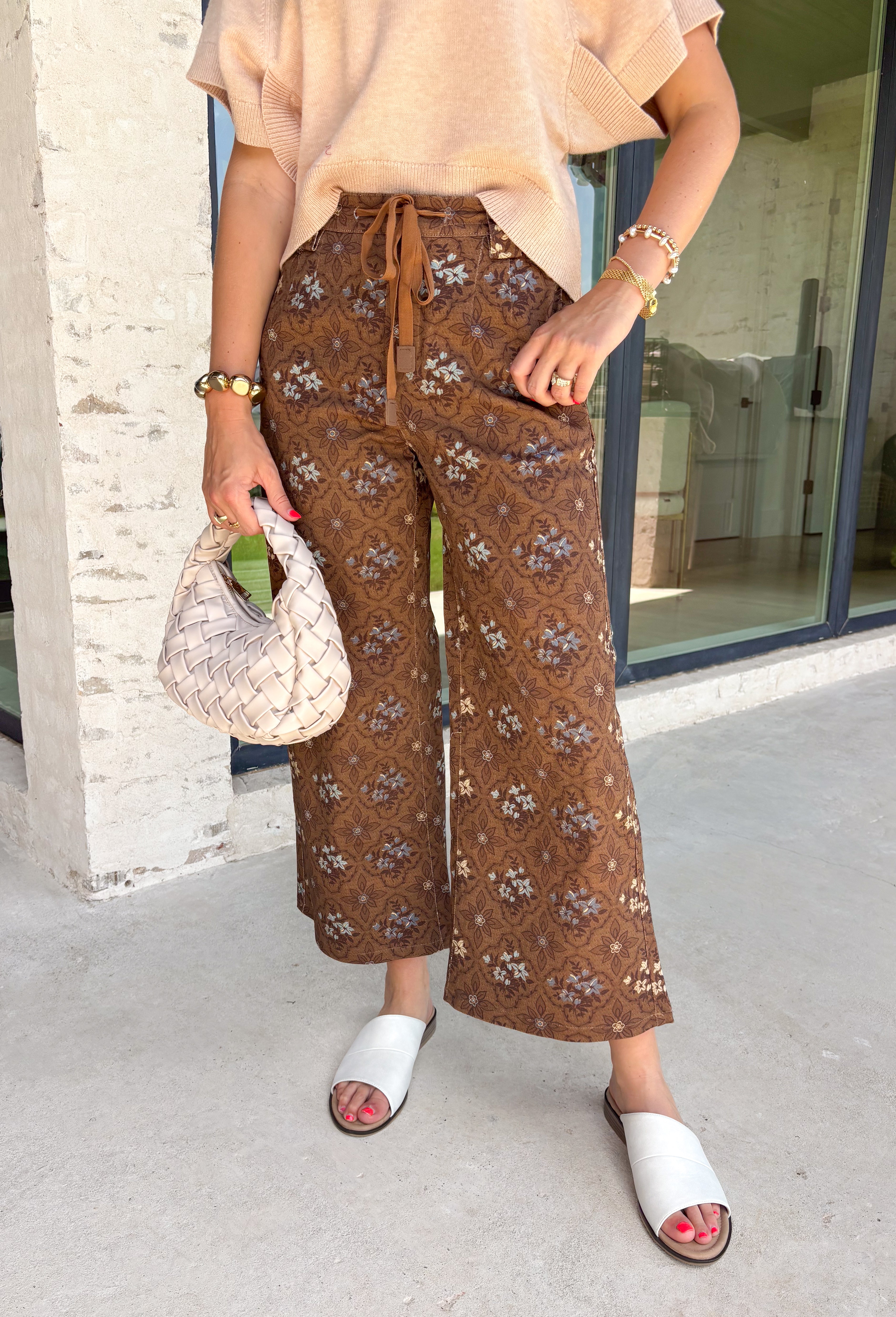 Give your everyday denim a fresh seasonal update with these statement-making wide leg jeans from Entro. Designed in a rich brown hue, these eye-catching pants feature a beautiful neutral floral print with subtle pops of blue for the perfect touch of color. The adjustable self-tie waist creates a flattering, customizable fit, while the wide leg silhouette offers effortless comfort and on-trend style. 