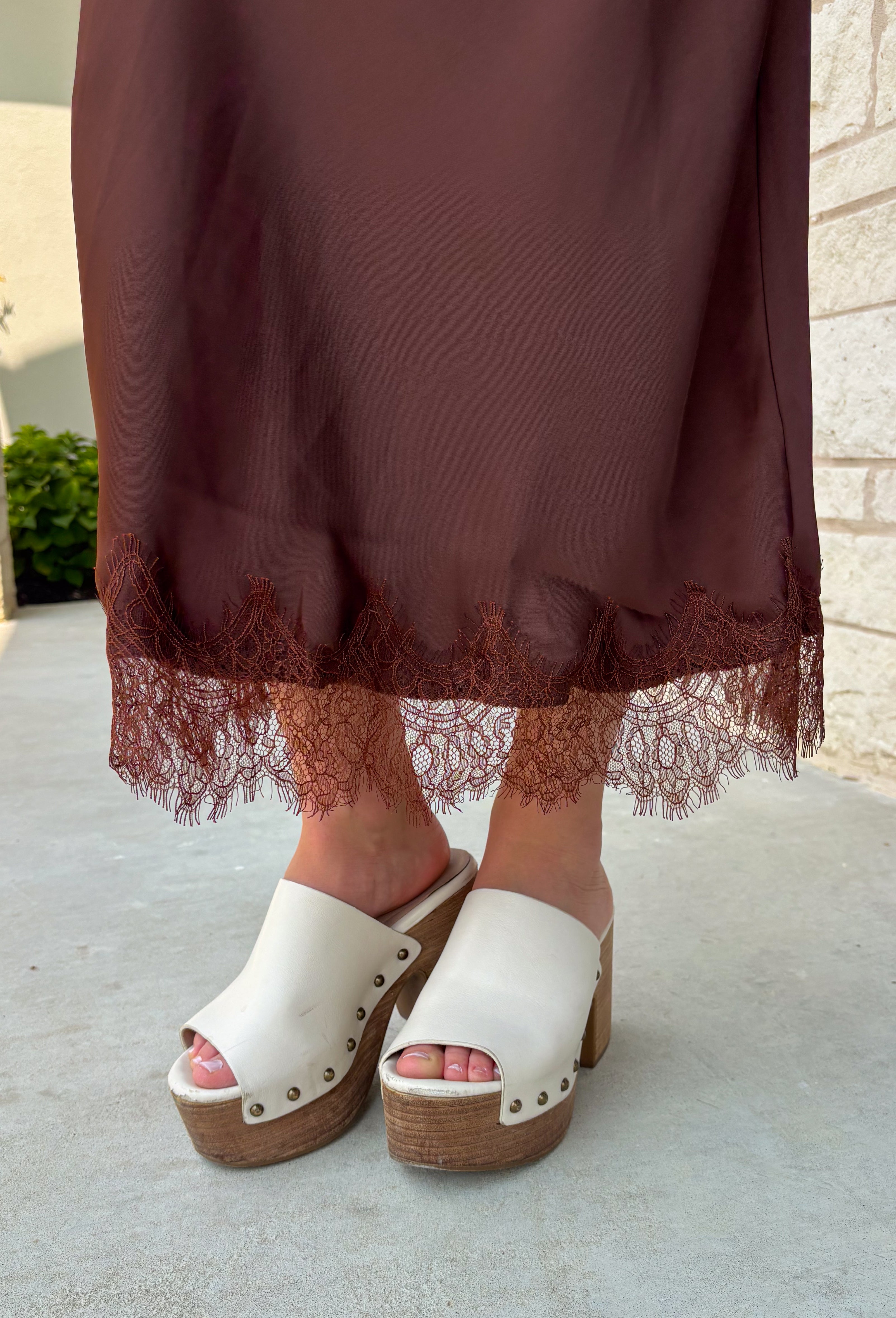 Bring a touch of romance to your fall wardrobe with this stunning chocolate brown satin midi skirt. Crafted from silky satin that catches the light beautifully, this chic skirt is finished with a delicate lace hem for an effortlessly feminine look. The elastic waistband offers all-day comfort while the side zipper creates a flattering, polished fit. Whether you're styling it for holiday gatherings, date nights, or elevating your everyday look, this timeless piece is one you'll love season after season.