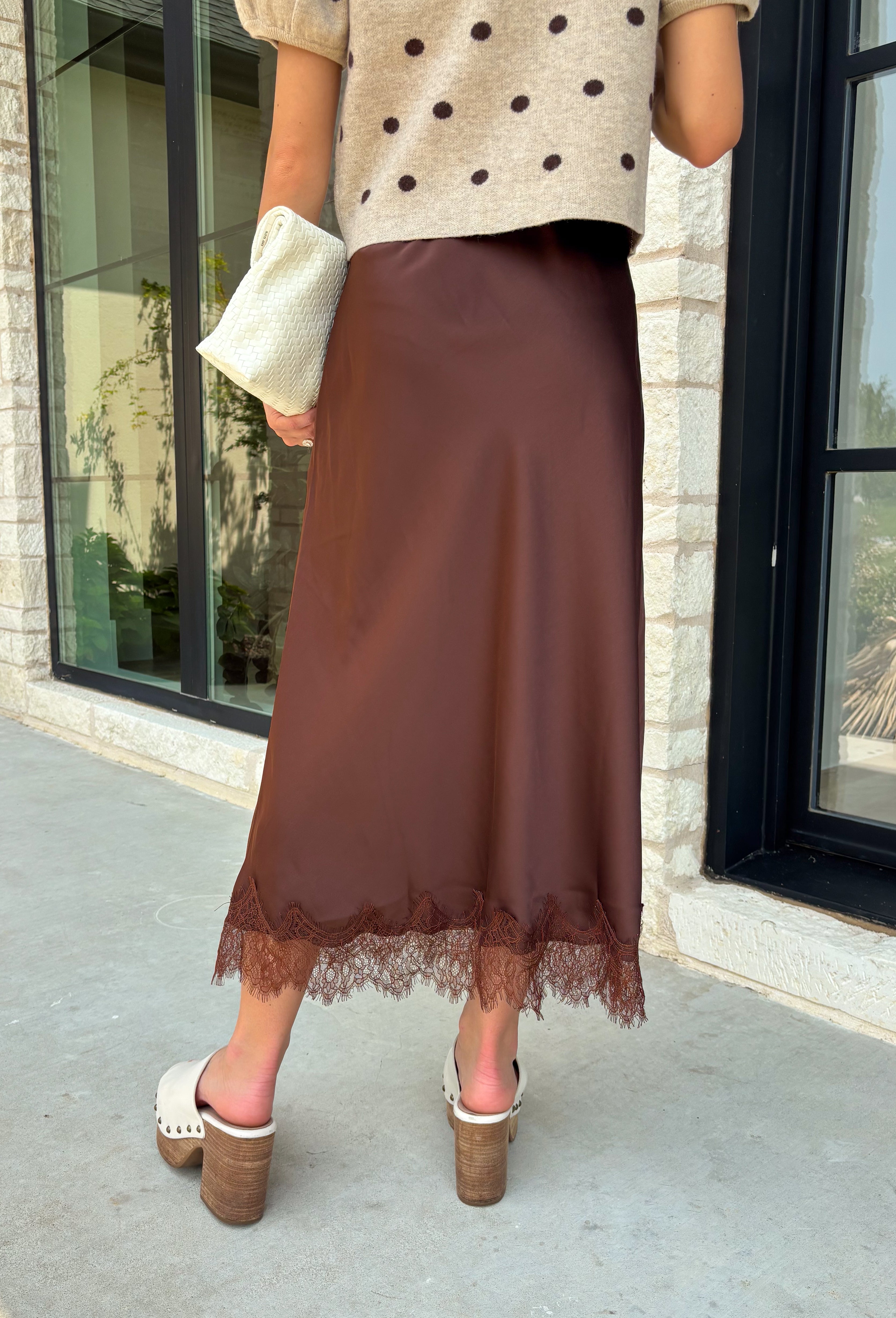 Bring a touch of romance to your fall wardrobe with this stunning chocolate brown satin midi skirt. Crafted from silky satin that catches the light beautifully, this chic skirt is finished with a delicate lace hem for an effortlessly feminine look. The elastic waistband offers all-day comfort while the side zipper creates a flattering, polished fit. Whether you're styling it for holiday gatherings, date nights, or elevating your everyday look, this timeless piece is one you'll love season after season.
