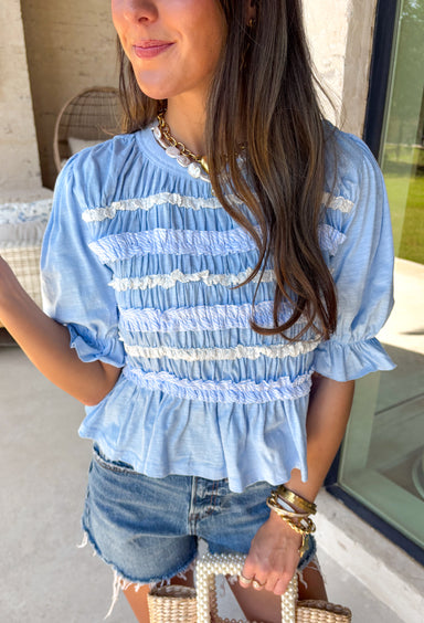 This blue lace ruffle top is such a dreamy piece for summer! With its delicate lace, layered ruffle details, and soft textured fabric, it brings the perfect mix of feminine and effortless style. The smocking throughout creates a flattering, comfortable fit while adding beautiful dimension. Lightweight and breathable in 100% cotton, it’s ideal for warm days when you still want something a little elevated. 