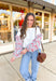 White pullover with long sleeves that features a mini floral print in red, blue, green, pink and white styled with wide leg jeans and a brown shoulder bag.