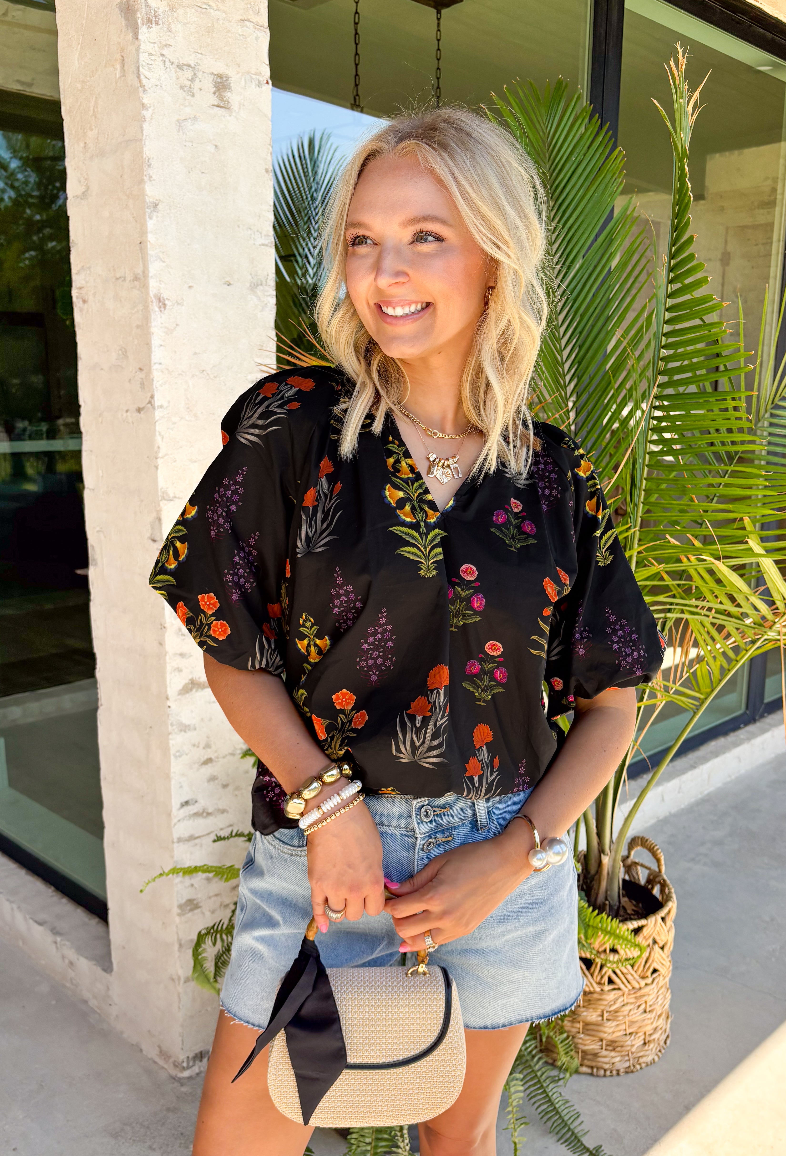 This black floral top is such a fun, vibrant pick for summer! The colorful mix of yellow, orange, purple, and green pops beautifully against the black base, making it an easy statement piece. The scalloped neckline and hem add the sweetest feminine detail, while the puff sleeves with elastic give it that flattering, easy shape. Lightweight and breathable in 100% cotton, it’s perfect for warm days when you still want to feel put together. 