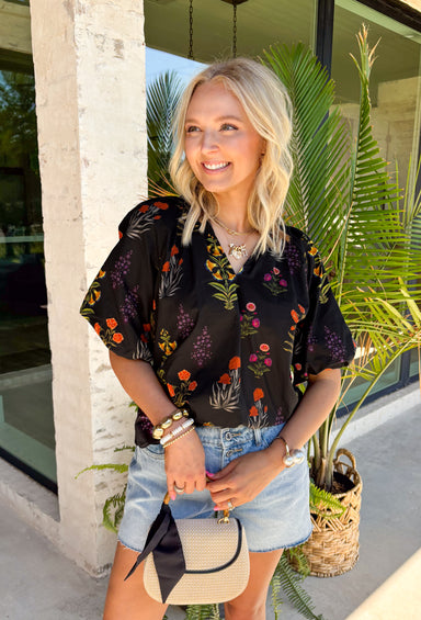 This black floral top is such a fun, vibrant pick for summer! The colorful mix of yellow, orange, purple, and green pops beautifully against the black base, making it an easy statement piece. The scalloped neckline and hem add the sweetest feminine detail, while the puff sleeves with elastic give it that flattering, easy shape. Lightweight and breathable in 100% cotton, it’s perfect for warm days when you still want to feel put together. 