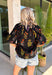 This black floral top is such a fun, vibrant pick for summer! The colorful mix of yellow, orange, purple, and green pops beautifully against the black base, making it an easy statement piece. The scalloped neckline and hem add the sweetest feminine detail, while the puff sleeves with elastic give it that flattering, easy shape. Lightweight and breathable in 100% cotton, it’s perfect for warm days when you still want to feel put together. 