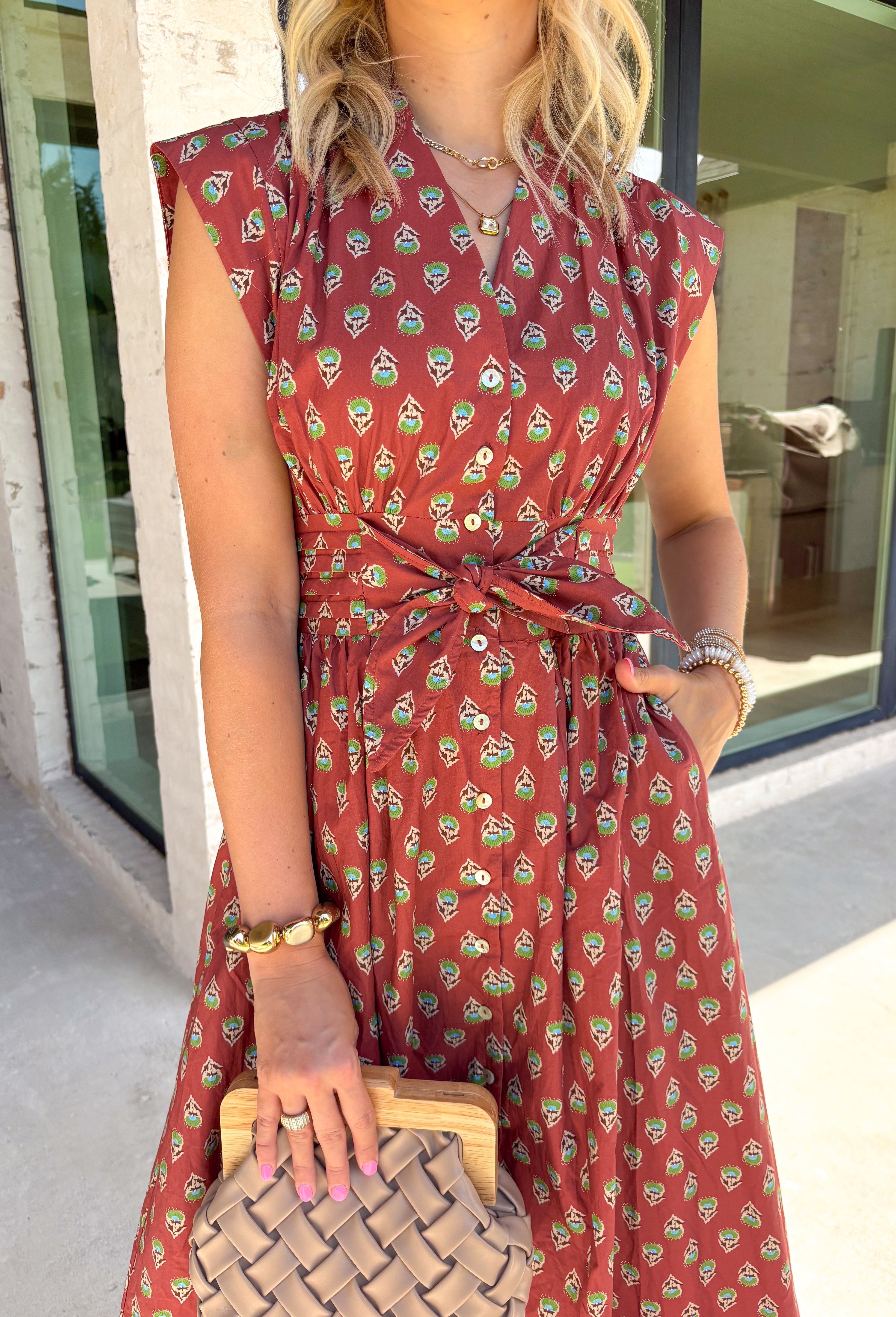 Capture the beauty of the season in this effortlessly charming rust midi dress. Featuring an abstract dainty floral and geo-inspired print with subtle pops of green, blue, and tan, this dress brings the perfect touch of autumn color to your wardrobe. The elastic waist with a self-tie detail creates a flattering, comfortable fit, while the button front and flowing midi silhouette give it timeless appeal. 
