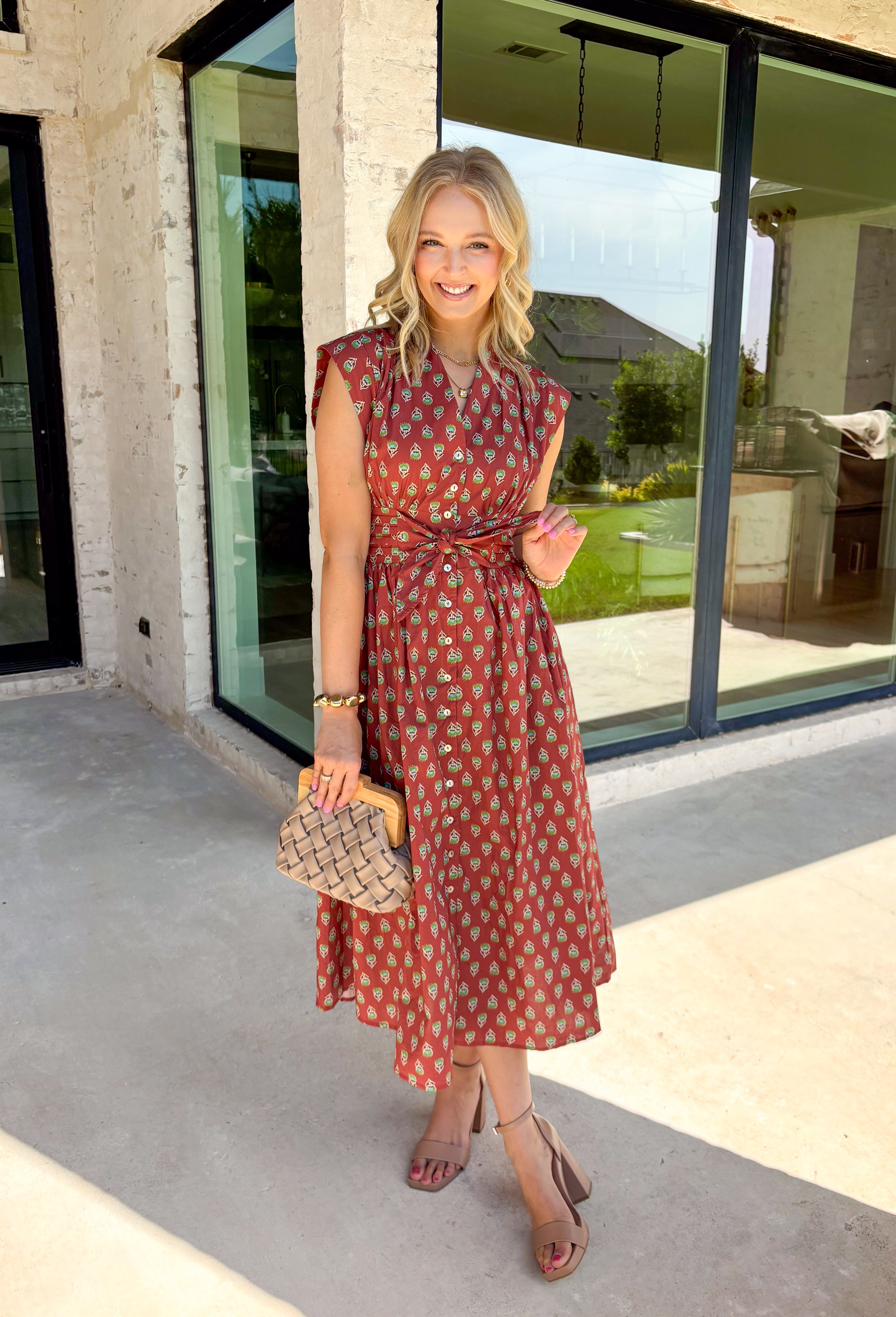 Capture the beauty of the season in this effortlessly charming rust midi dress. Featuring an abstract dainty floral and geo-inspired print with subtle pops of green, blue, and tan, this dress brings the perfect touch of autumn color to your wardrobe. The elastic waist with a self-tie detail creates a flattering, comfortable fit, while the button front and flowing midi silhouette give it timeless appeal. 
