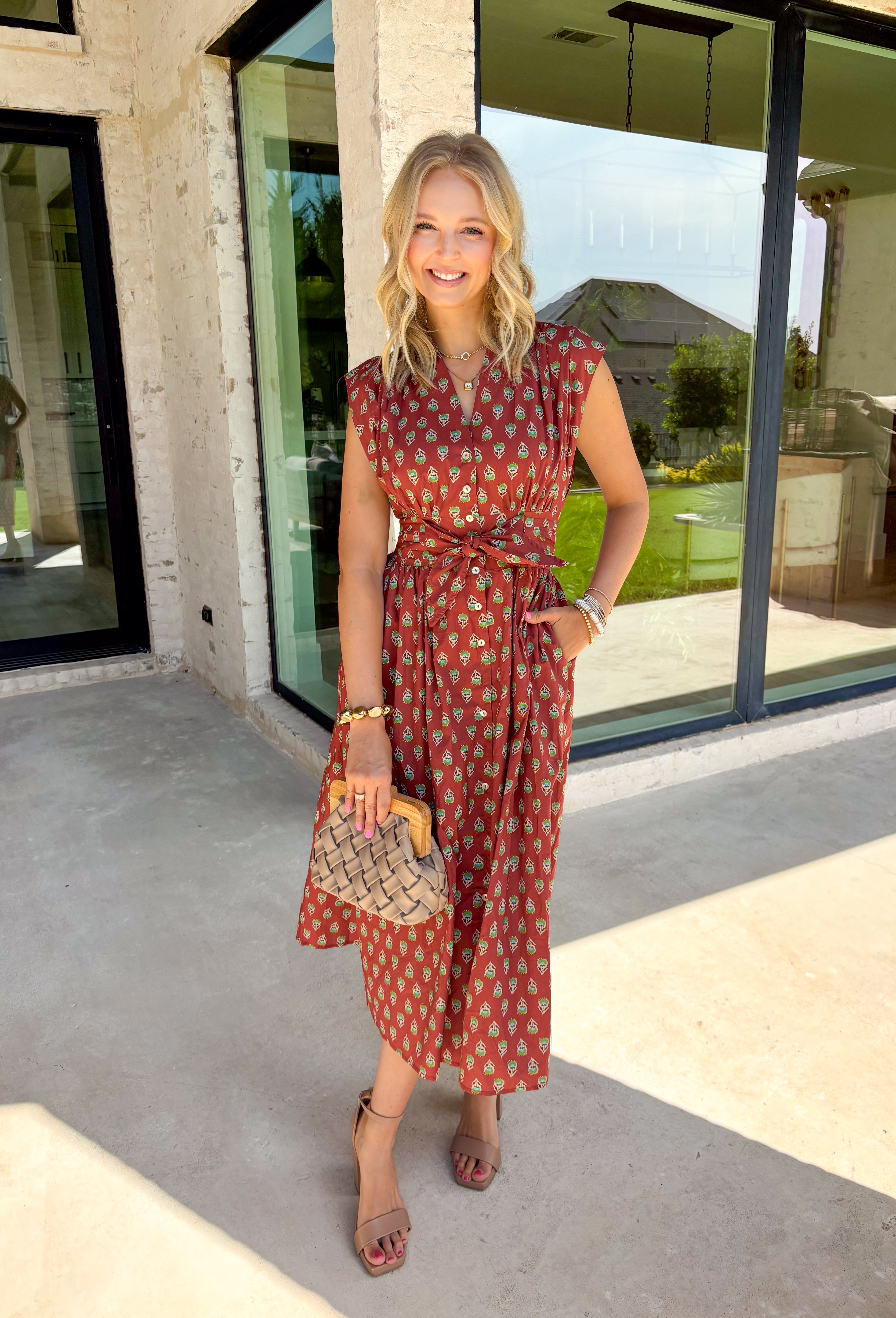 Capture the beauty of the season in this effortlessly charming rust midi dress. Featuring an abstract dainty floral and geo-inspired print with subtle pops of green, blue, and tan, this dress brings the perfect touch of autumn color to your wardrobe. The elastic waist with a self-tie detail creates a flattering, comfortable fit, while the button front and flowing midi silhouette give it timeless appeal. 
