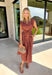 Capture the beauty of the season in this effortlessly charming rust midi dress. Featuring an abstract dainty floral and geo-inspired print with subtle pops of green, blue, and tan, this dress brings the perfect touch of autumn color to your wardrobe. The elastic waist with a self-tie detail creates a flattering, comfortable fit, while the button front and flowing midi silhouette give it timeless appeal. 
