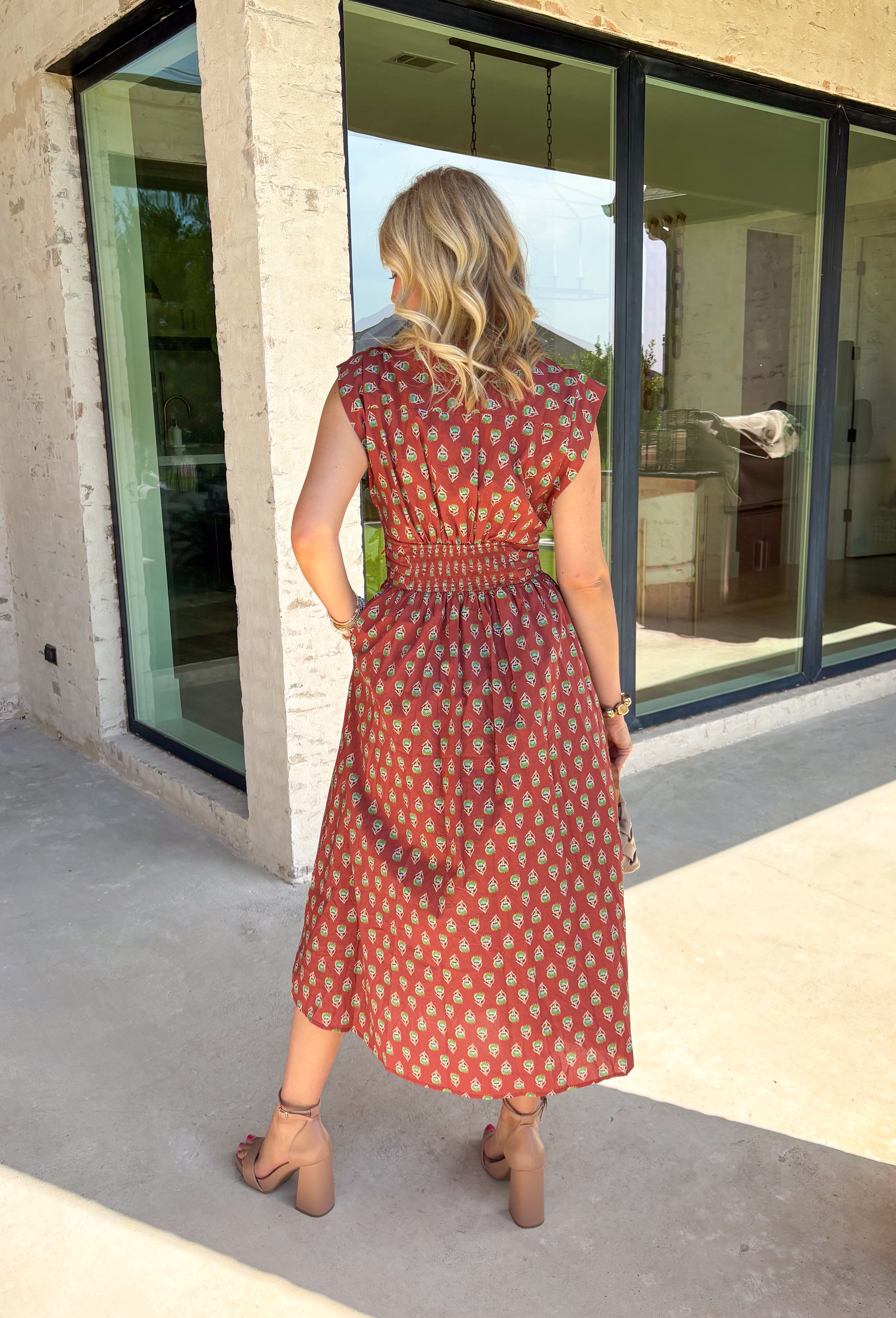 Capture the beauty of the season in this effortlessly charming rust midi dress. Featuring an abstract dainty floral and geo-inspired print with subtle pops of green, blue, and tan, this dress brings the perfect touch of autumn color to your wardrobe. The elastic waist with a self-tie detail creates a flattering, comfortable fit, while the button front and flowing midi silhouette give it timeless appeal. 
