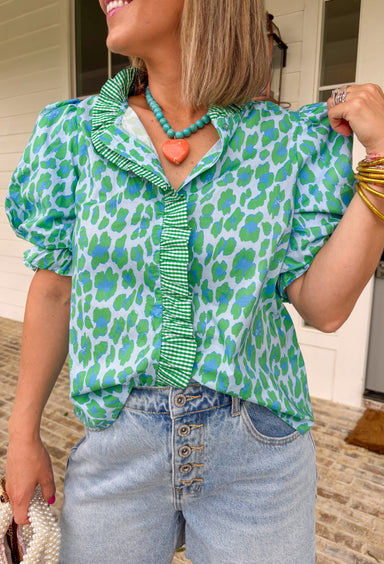 This leopard print puff sleeve top is such a fun, standout piece for summer! The light blue base with green and blue leopard print gives it a fresh, unexpected twist, while the green and white gingham ruffle trim adds the cutest pop of contrast. The band collar and button front keep it feeling polished, and the puff sleeves with elastic openings bring that soft, feminine shape. Made from breathable cotton, it’s perfect for warm days when you still want to feel put together. Pair it with white denim or short