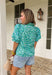 This leopard print puff sleeve top is such a fun, standout piece for summer! The light blue base with green and blue leopard print gives it a fresh, unexpected twist, while the green and white gingham ruffle trim adds the cutest pop of contrast. The band collar and button front keep it feeling polished, and the puff sleeves with elastic openings bring that soft, feminine shape. Made from breathable cotton, it’s perfect for warm days when you still want to feel put together. Pair it with white denim or short