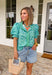 This leopard print puff sleeve top is such a fun, standout piece for summer! The light blue base with green and blue leopard print gives it a fresh, unexpected twist, while the green and white gingham ruffle trim adds the cutest pop of contrast. The band collar and button front keep it feeling polished, and the puff sleeves with elastic openings bring that soft, feminine shape. Made from breathable cotton, it’s perfect for warm days when you still want to feel put together. Pair it with white denim or short