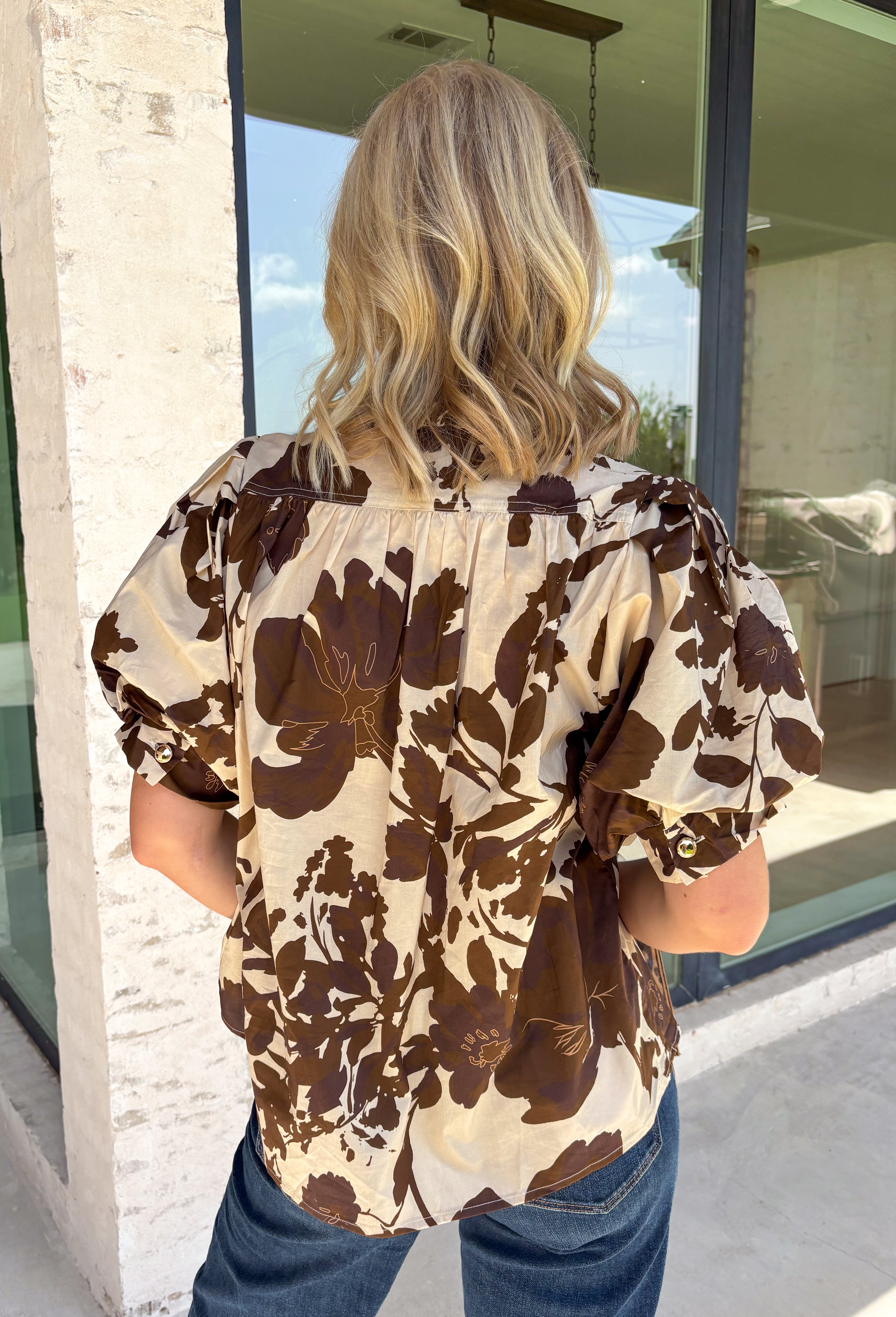 Classic florals and elevated details make this blouse a beautiful addition to your fall wardrobe. Designed with a cream backdrop and a rich brown floral print, this timeless top offers an effortlessly polished look that's perfect for both work and weekends. The stand neckline creates a refined silhouette, while the gleaming gold button-front closure adds an elegant finishing touch. 