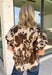 Classic florals and elevated details make this blouse a beautiful addition to your fall wardrobe. Designed with a cream backdrop and a rich brown floral print, this timeless top offers an effortlessly polished look that's perfect for both work and weekends. The stand neckline creates a refined silhouette, while the gleaming gold button-front closure adds an elegant finishing touch. 