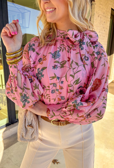 Soft, flowy, and full of spring charm, this pink long sleeve top by Entro is an effortless standout. Featuring a beautiful floral print with pops of green, blue, and brick, it brings the perfect mix of color while still feeling easy to wear. The matching self-tie neckline adds a sweet, elevated touch, and the balloon sleeves give it a romantic silhouette that feels light and breezy. Made from a silky tencel blend, this top drapes beautifully and feels amazing on.