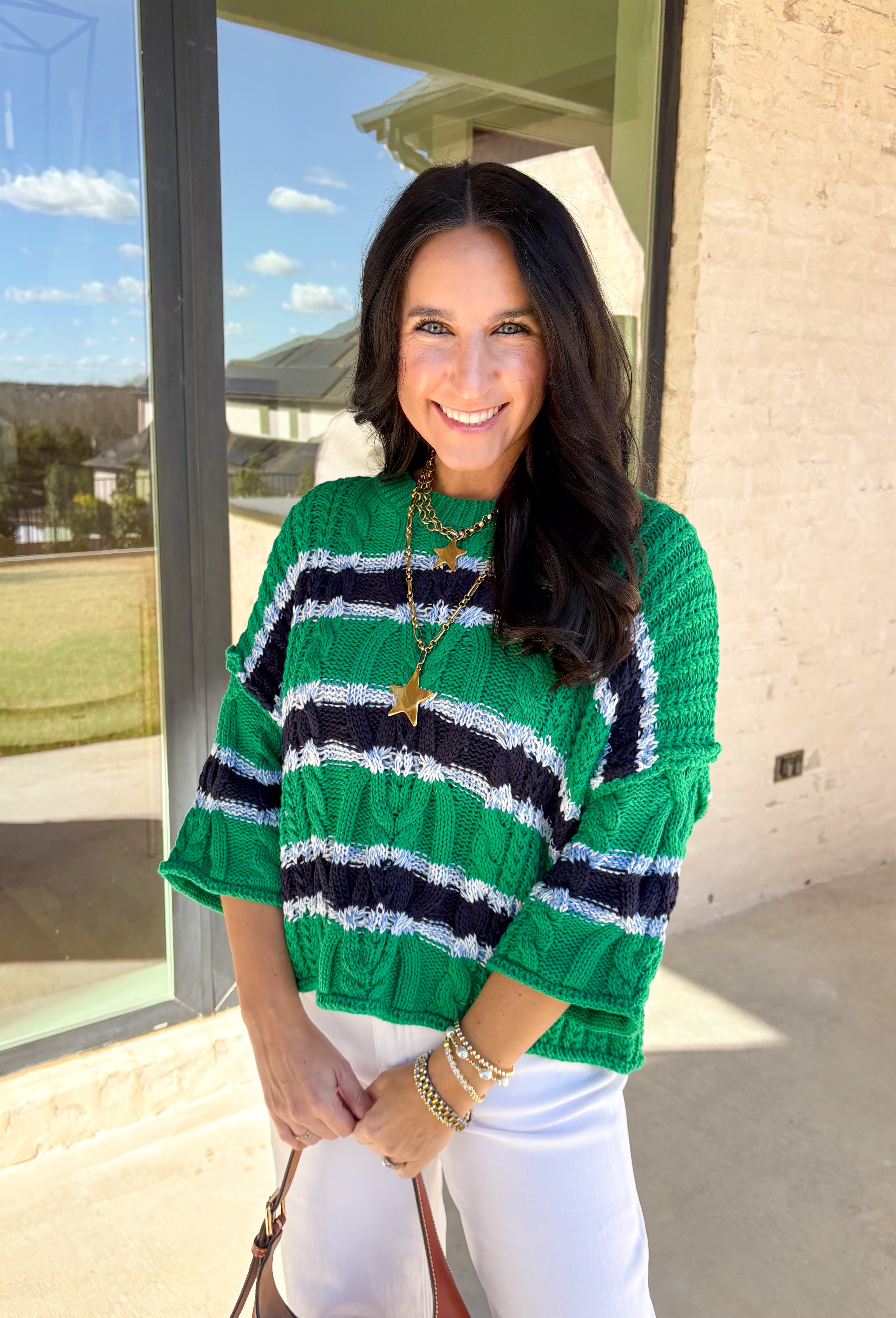 Classic with a fresh spring twist, this striped knit sweater by Entro is an easy piece to reach for on cooler spring days. Featuring a round neckline and ¾ length sleeves, it’s finished with subtle cable knit detailing that adds texture without feeling heavy. The green base is accented with black, blue, and white stripes, giving it a timeless look that pairs effortlessly with denim, trousers, or skirts.