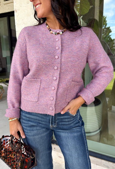Wrap yourself in all the cozy vibes this season with this beautiful knit cardigan! Featuring gorgeous shades of purple woven throughout, this button-down cardigan is the perfect layering piece for crisp autumn mornings and cozy evenings. Front pockets add a practical touch, while the soft knit fabric makes it one you'll reach for again and again. Whether you're heading to brunch, the office, or enjoying a weekend at the pumpkin patch, this cardigan brings effortless comfort and style to every outfit.