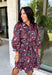 Celebrate the beauty of fall in this effortlessly chic dress from Entro. Designed with a rich brown backdrop and a beautiful floral and leaf print in autumn shades, this timeless dress is full of charming details. The classic shirt collar and button-front closure create a polished look, while the self-tie belt and elastic back waist provide a flattering, comfortable fit. Finished with ¾ balloon sleeves, a feminine tiered hem, convenient side pockets, and a fully lined design.