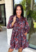 Celebrate the beauty of fall in this effortlessly chic dress from Entro. Designed with a rich brown backdrop and a beautiful floral and leaf print in autumn shades, this timeless dress is full of charming details. The classic shirt collar and button-front closure create a polished look, while the self-tie belt and elastic back waist provide a flattering, comfortable fit. Finished with ¾ balloon sleeves, a feminine tiered hem, convenient side pockets, and a fully lined design.
