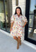 Bring a touch of color to your fall wardrobe with this effortlessly charming botanical dress. Featuring a neutral backdrop with a vibrant floral print, this feminine dress is perfect for everything from brunch dates to fall festivals. The adjustable drawstring waist creates a flattering silhouette, while the collared v-neckline and partial button placket add a timeless touch. Finished with sweet tie details at the sleeves, side pockets, and a fully lined design.