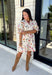 Bring a touch of color to your fall wardrobe with this effortlessly charming botanical dress. Featuring a neutral backdrop with a vibrant floral print, this feminine dress is perfect for everything from brunch dates to fall festivals. The adjustable drawstring waist creates a flattering silhouette, while the collared v-neckline and partial button placket add a timeless touch. Finished with sweet tie details at the sleeves, side pockets, and a fully lined design.
