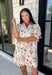 Bring a touch of color to your fall wardrobe with this effortlessly charming botanical dress. Featuring a neutral backdrop with a vibrant floral print, this feminine dress is perfect for everything from brunch dates to fall festivals. The adjustable drawstring waist creates a flattering silhouette, while the collared v-neckline and partial button placket add a timeless touch. Finished with sweet tie details at the sleeves, side pockets, and a fully lined design.