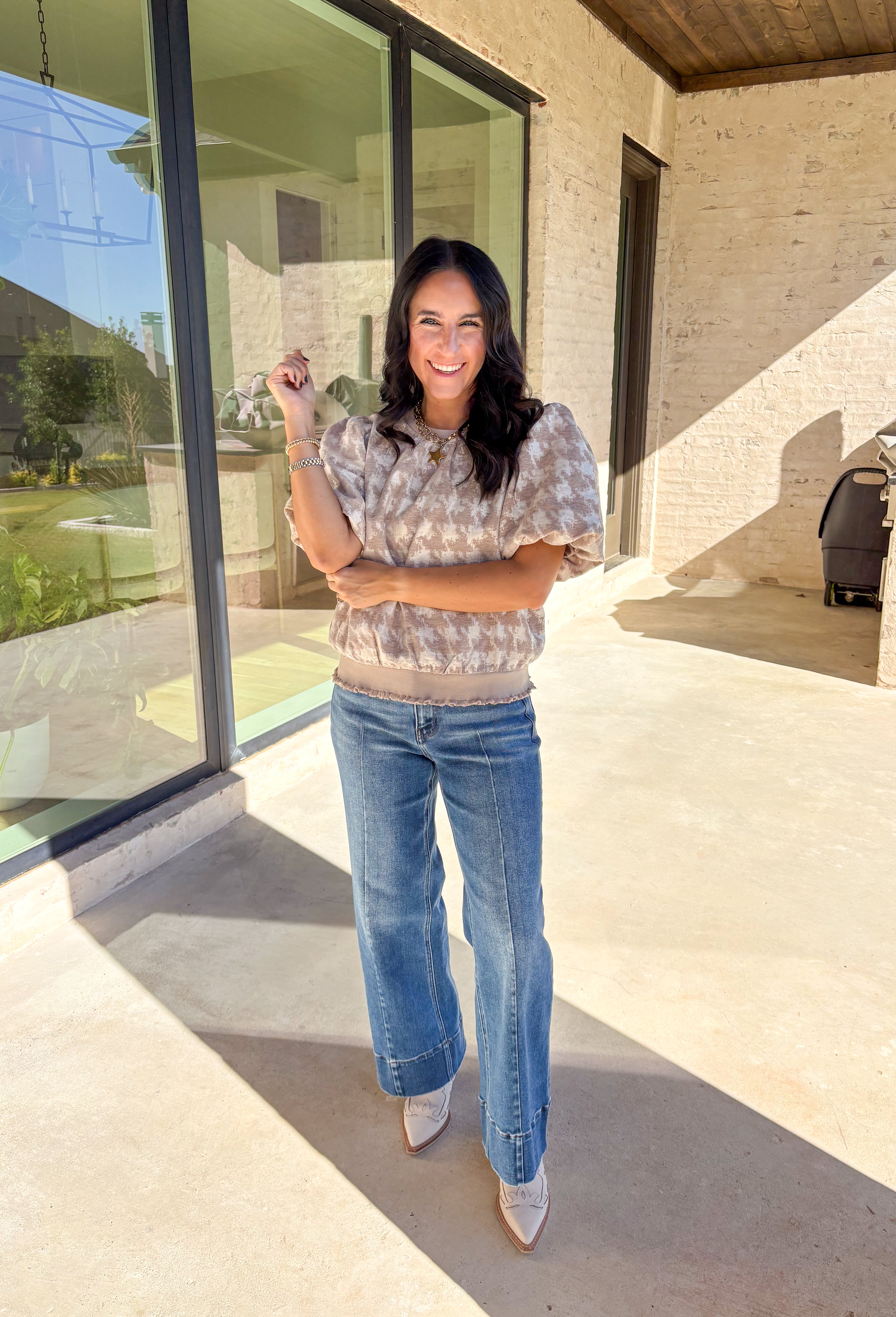 This taupe short sleeve top by Voy gives a modern twist to a timeless print. Designed with a textured abstract houndstooth pattern, it’s the perfect mix of classic and contemporary. The puff sleeves add a soft, feminine touch, while the lettuce hem brings a subtle edge to the silhouette. Lightweight and comfortable, this top easily transitions from weekday wear to special occasions.