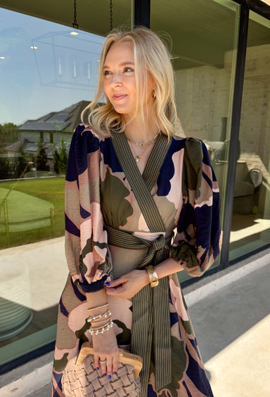 All the colors we love for fall come together in this printed midi dress from Entro. A mix of olive, navy, and tan creates a rich seasonal palette that feels right at home at autumn gatherings, family photos, and weekend plans. The v-neckline is accented with contrast stripe trim for a fun mix of prints, while long balloon sleeves add beautiful shape to the silhouette. A coordinating self-tie belt lets you define the waist, and convenient side pockets make it even easier to wear. 