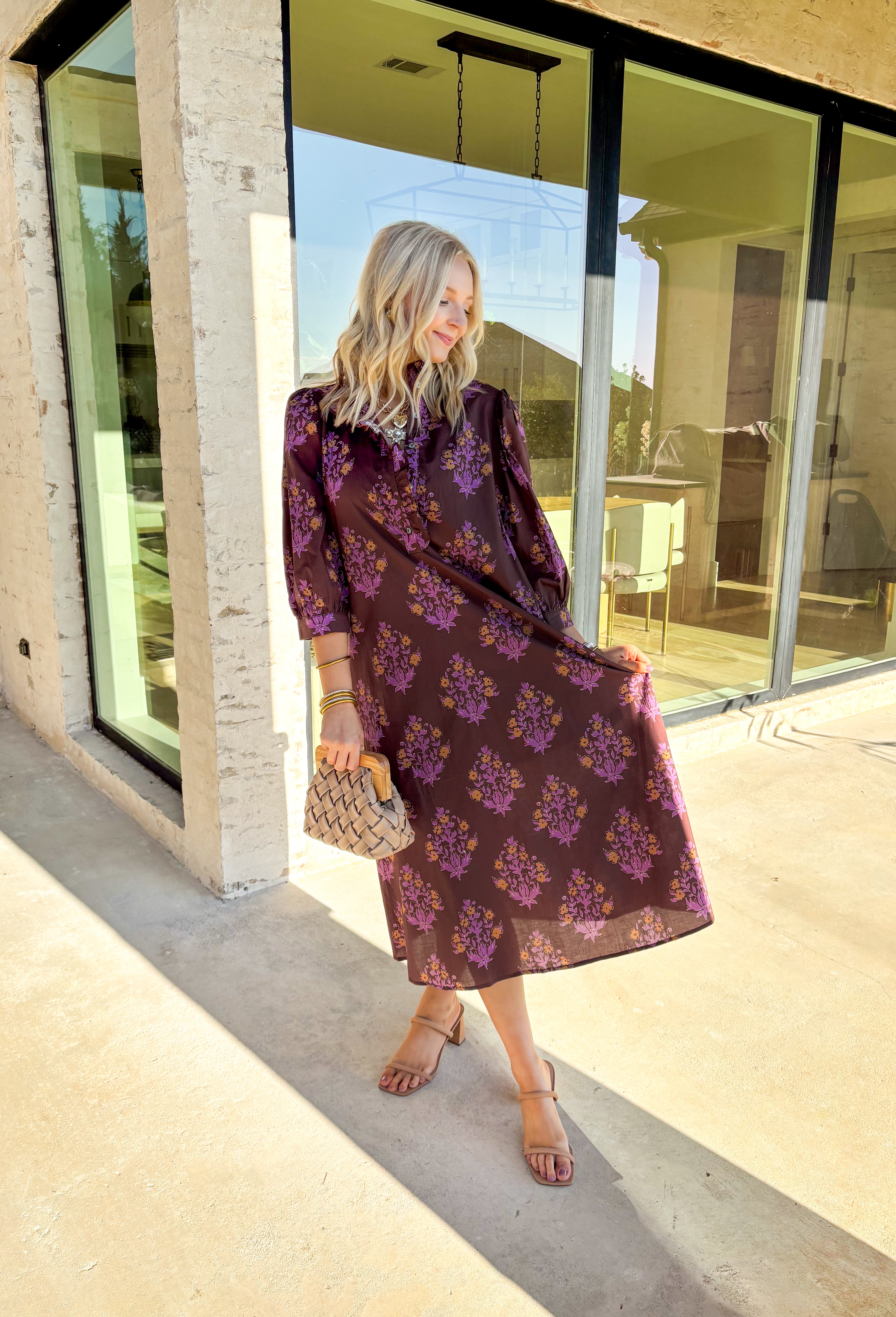 Earthy tones meet feminine charm in this beautiful botanical print midi dress by Entro. Designed with ¾ sleeves and a soft ruffle trim along the collar and front placket, it’s full of subtle details that make it feel special. The button-front design and side pockets bring functionality, while the brown base with purple and dark yellow florals gives it that perfect fall color palette. Fully lined and made from breathable cotton, it’s comfortable enough for all-day wear while keeping your look effortlessly po