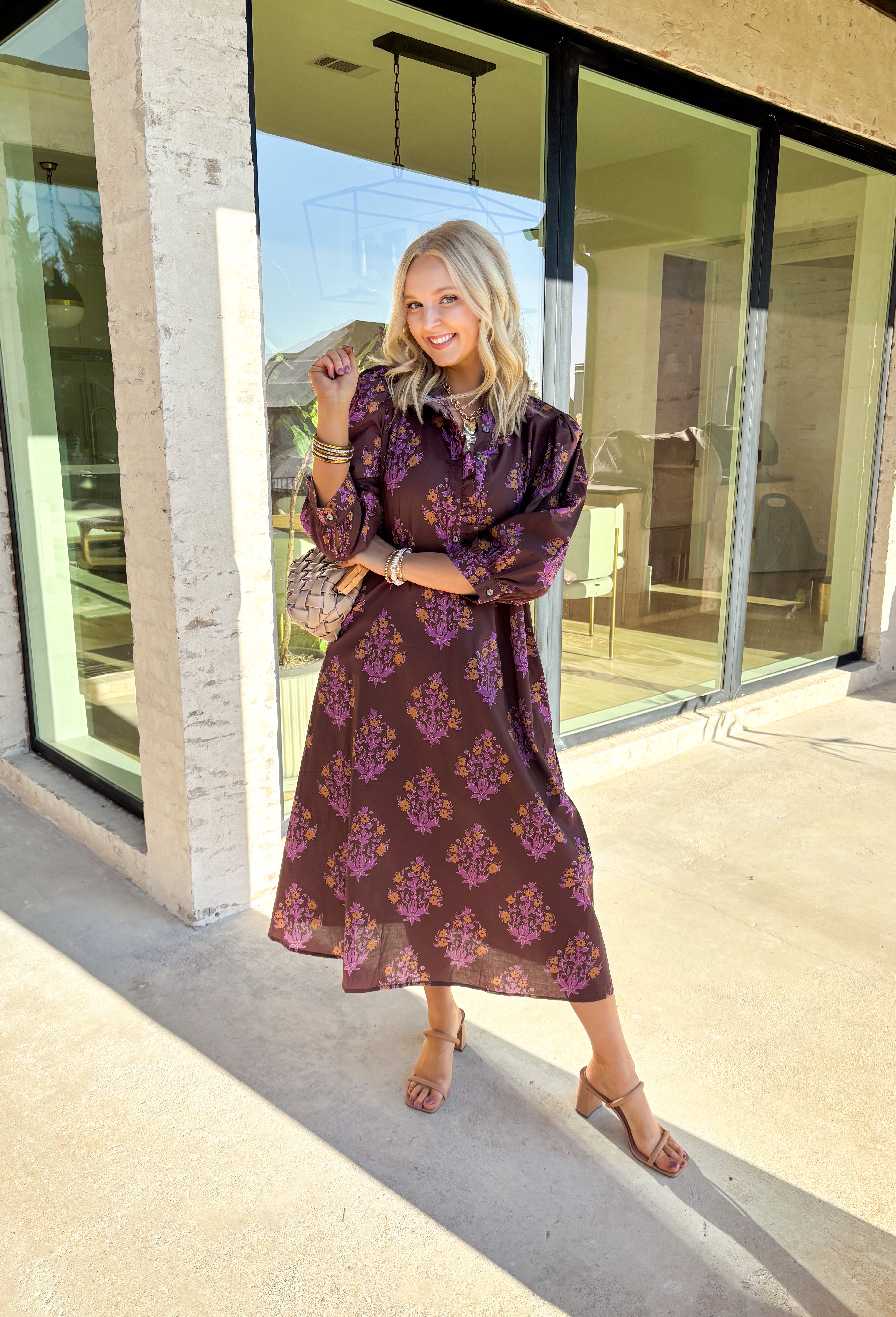 Earthy tones meet feminine charm in this beautiful botanical print midi dress by Entro. Designed with ¾ sleeves and a soft ruffle trim along the collar and front placket, it’s full of subtle details that make it feel special. The button-front design and side pockets bring functionality, while the brown base with purple and dark yellow florals gives it that perfect fall color palette. Fully lined and made from breathable cotton, it’s comfortable enough for all-day wear while keeping your look effortlessly po