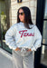 Show your Texas pride in the coziest way possible! This ash grey mock neck sweatshirt blends everyday comfort with timeless style, featuring "Texas" in soft script across the chest and a sweet heart detail on the sleeve. The fleece-lined interior keeps you warm and cozy, while the classic silhouette makes it an easy favorite for everything from football Saturdays and coffee runs to relaxed weekends at home. 