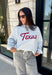 Show your Texas pride in the coziest way possible! This ash grey mock neck sweatshirt blends everyday comfort with timeless style, featuring "Texas" in soft script across the chest and a sweet heart detail on the sleeve. The fleece-lined interior keeps you warm and cozy, while the classic silhouette makes it an easy favorite for everything from football Saturdays and coffee runs to relaxed weekends at home. 