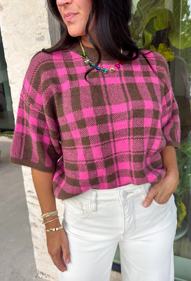 Add a cozy pop of pattern to your everyday wardrobe with this charming sweater from Entro. Designed in a pink and brown plaid knit, this short sleeve sweater is the perfect blend of classic style and seasonal warmth. The soft, cozy knit makes it comfortable enough for all-day wear, while the timeless plaid pattern adds effortless charm to any outfit. 