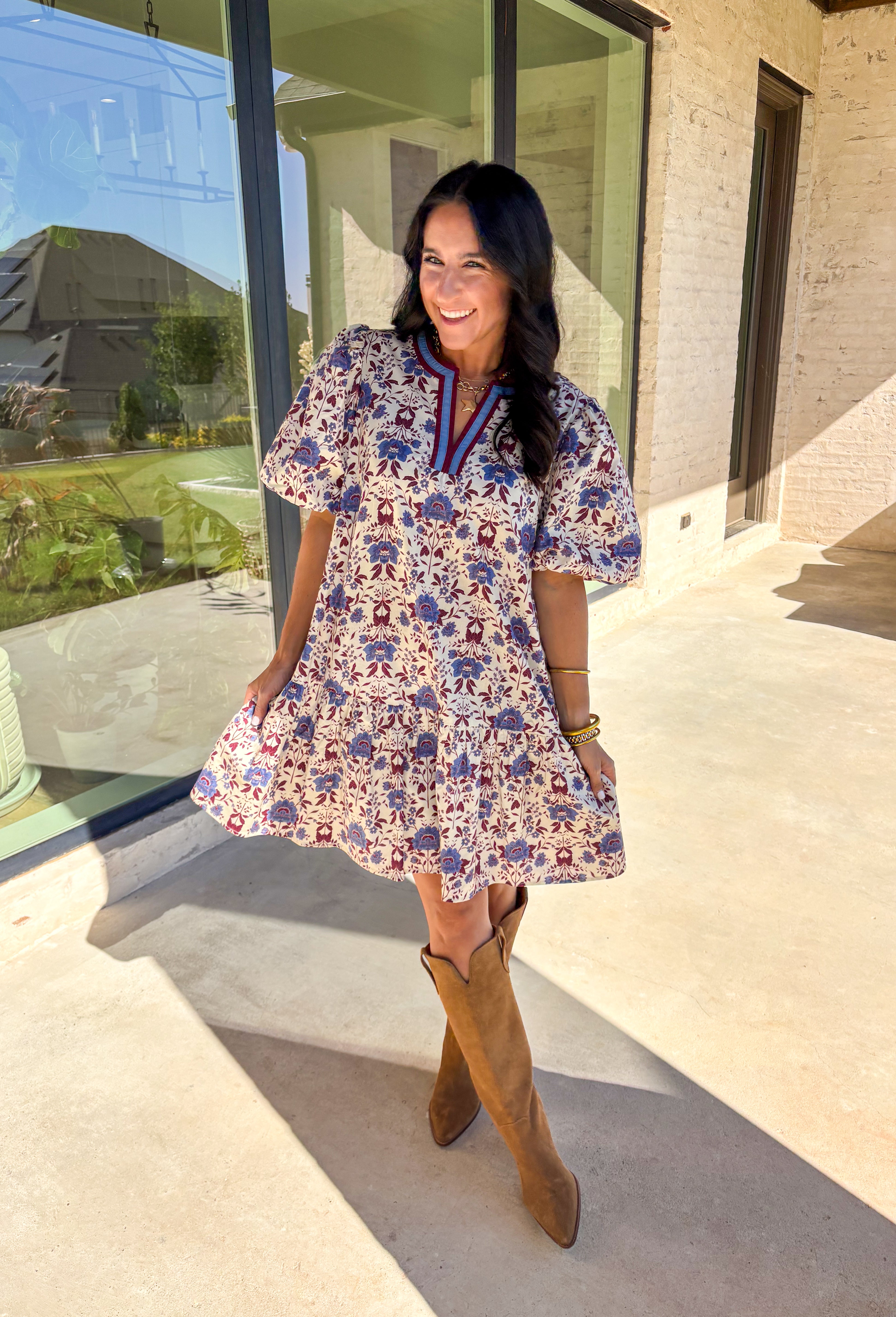 Romantic florals meet cozy charm in this cream short sleeve dress. Designed with shades of burgundy and blue for an autumn-inspired palette, it features a botanical print and contrast binding along the v-neckline for a polished finish. The puff sleeves add a playful touch, while the ruffle hem brings soft movement. Fully lined with side pockets for practicality, this dress is as easy to wear as it is beautiful.