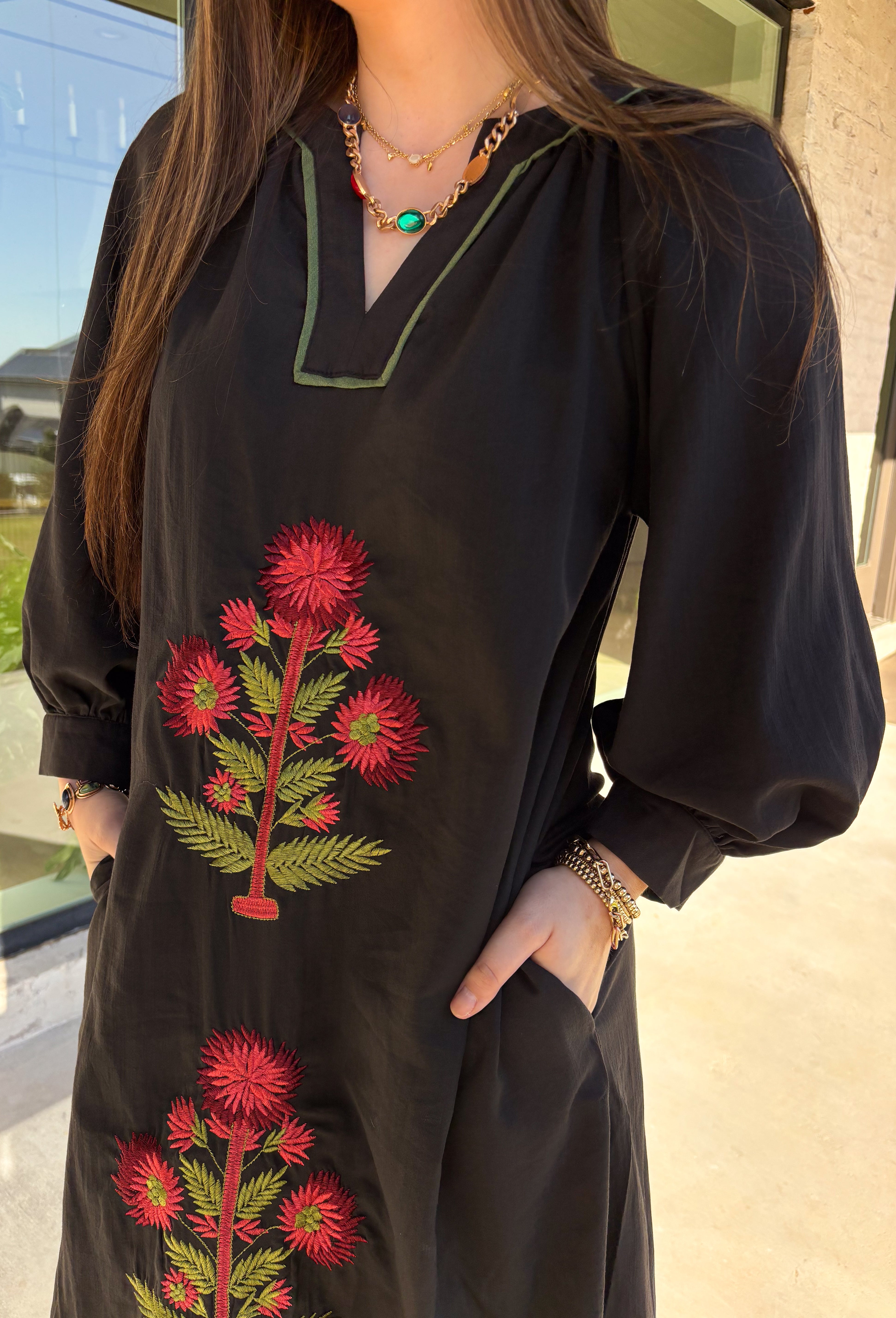 Bring elegance to the winter season with this stunning black embroidered midi dress by Entro. Featuring beautiful burgundy and olive floral embroidery, this long sleeve dress combines cozy sophistication with timeless charm. The contrast trim v-neck and subtle side slits add a touch of movement, while the fully lined design ensures comfort and warmth. Perfect for winter gatherings, holiday dinners, or date nights, this dress is effortlessly refined for the season.