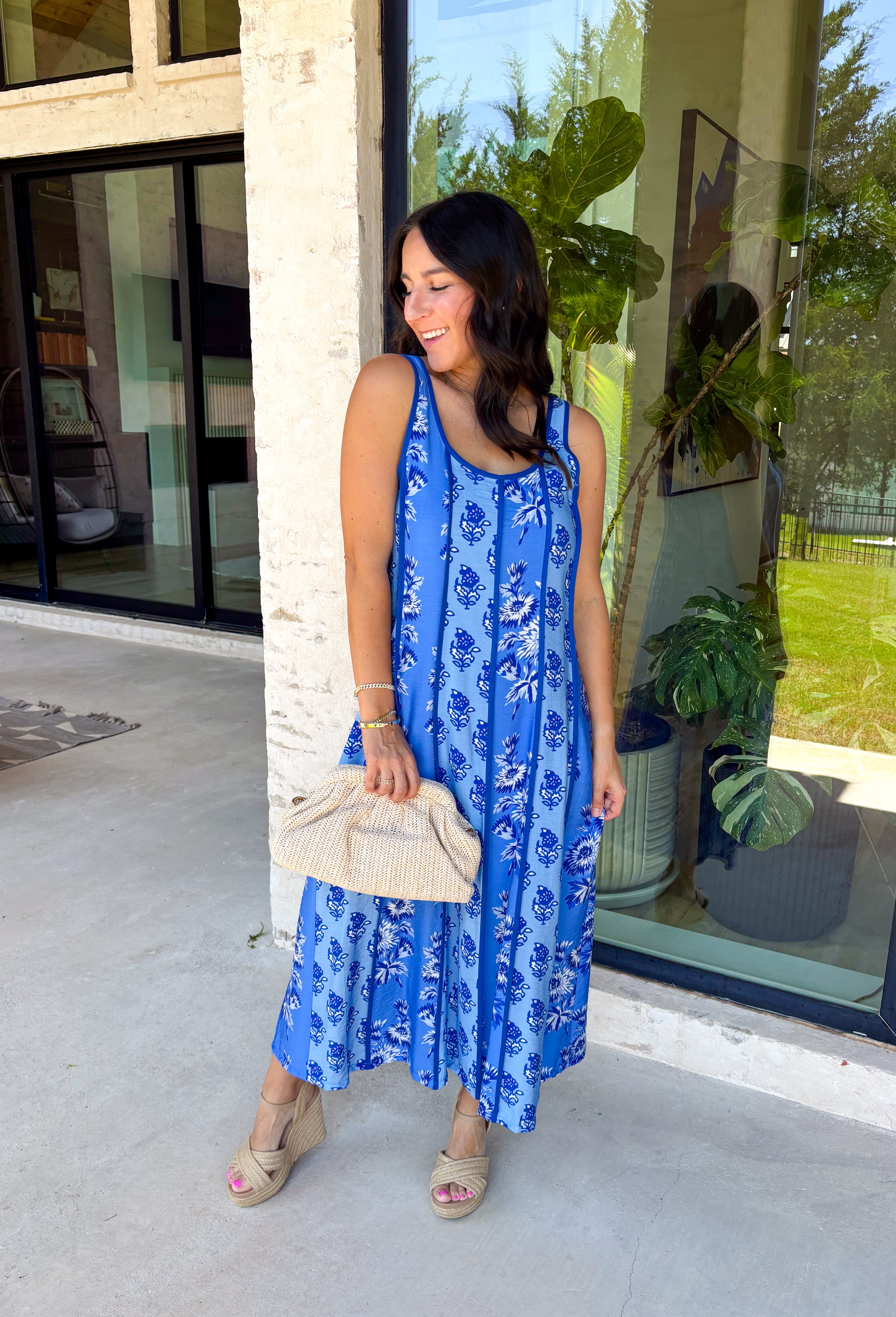 Feminine, fresh, and perfect for sunny days! This sleeveless blue midi dress features a beautiful floral print that feels soft and romantic. Darker blue trim paneling throughout adds a lovely contrast that highlights the silhouette and gives the dress a little extra detail. Smocking along the back and on the back straps creates a comfortable, flexible fit while keeping the shape flattering. 