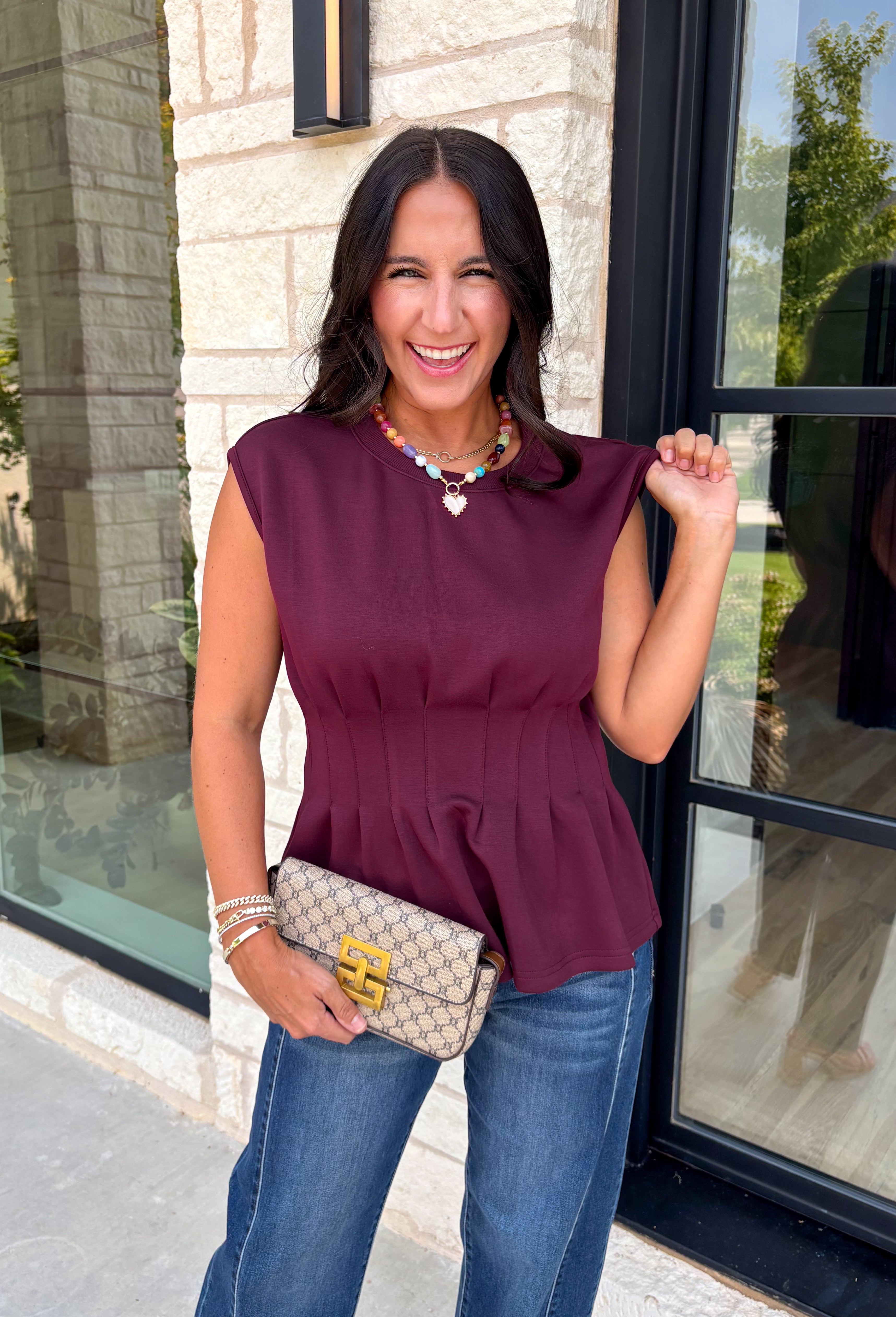 Rich seasonal color meets effortless style in this beautiful burgundy sleeveless top. Designed with flattering pleated waist detailing, this timeless piece creates a polished silhouette that's easy to dress up or down. The soft knit fabric offers all-day comfort, making it perfect for layering under blazers and jackets throughout the fall or wearing on its own during warmer autumn afternoons. 