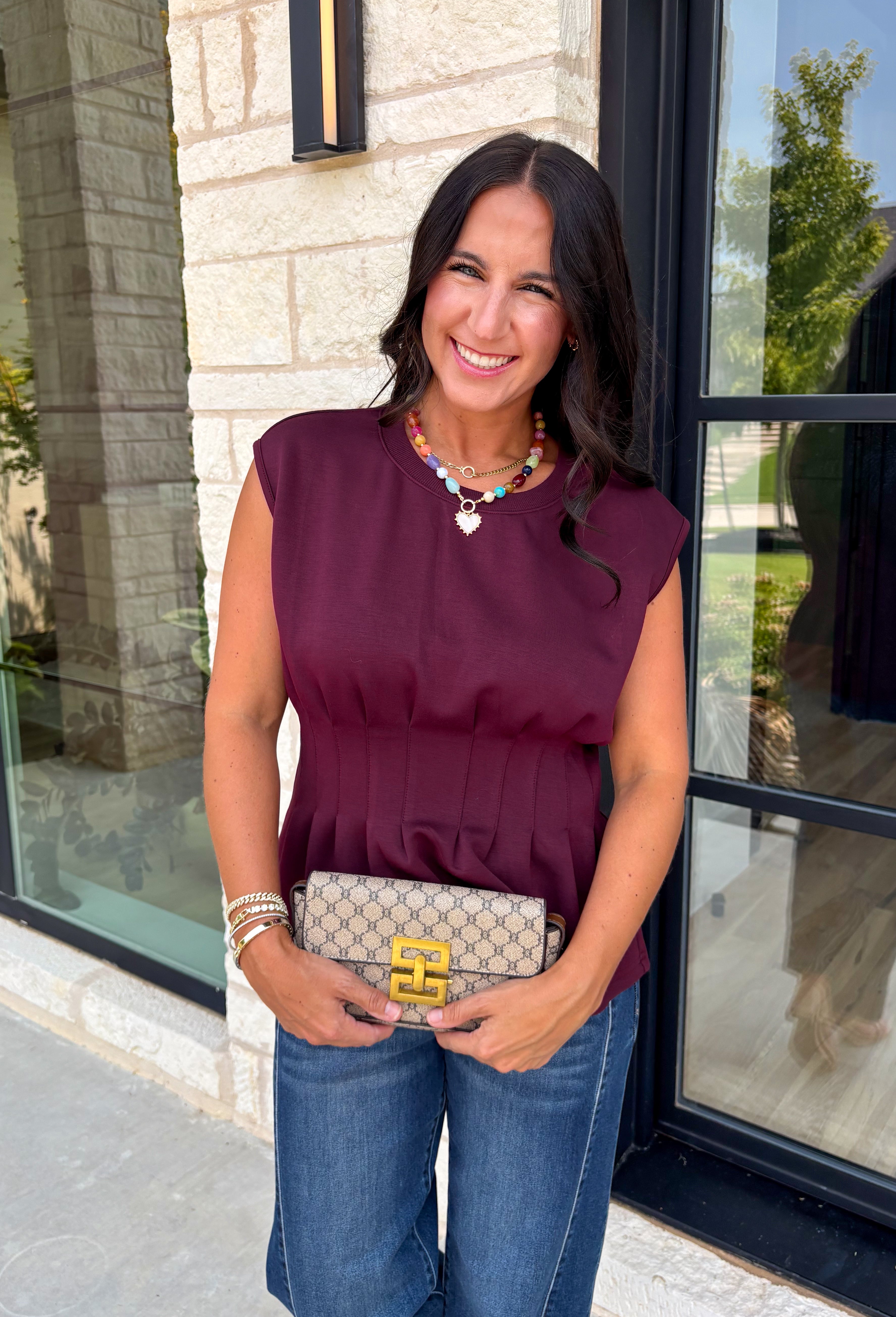 Rich seasonal color meets effortless style in this beautiful burgundy sleeveless top. Designed with flattering pleated waist detailing, this timeless piece creates a polished silhouette that's easy to dress up or down. The soft knit fabric offers all-day comfort, making it perfect for layering under blazers and jackets throughout the fall or wearing on its own during warmer autumn afternoons. 