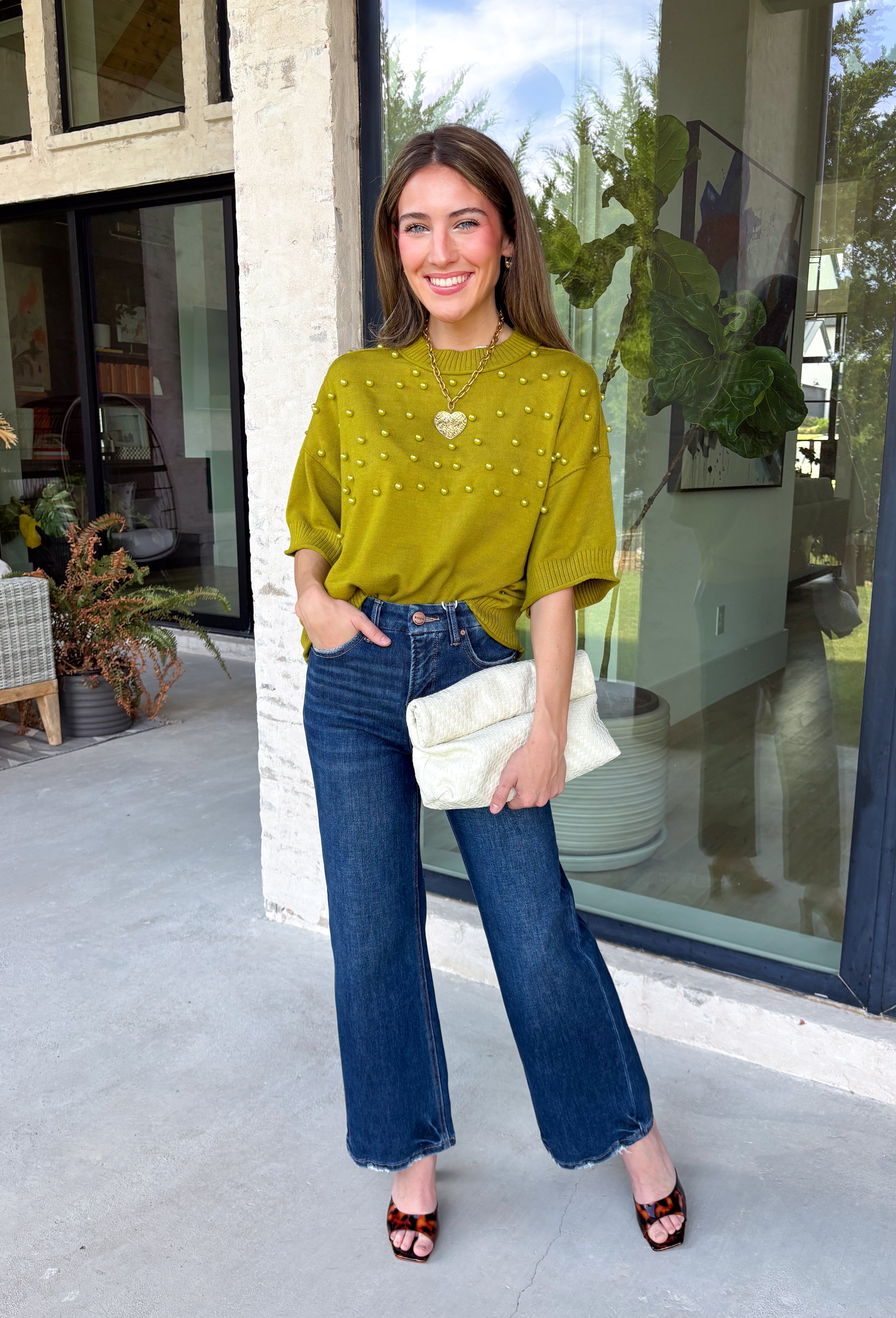 A rich olive green gets a pretty update with this pearl-detailed short sleeve sweater from Glam. Pearl detailing throughout adds a special touch to the soft knit, making it easy to dress up while still keeping that cozy, everyday feel. Exposed hems bring in a relaxed finish, while ribbed detailing along the neckline, sleeve cuffs, and hem gives it a classic sweater look. Wear it to the office, dinner plans, or anytime your outfit could use a little something extra.
