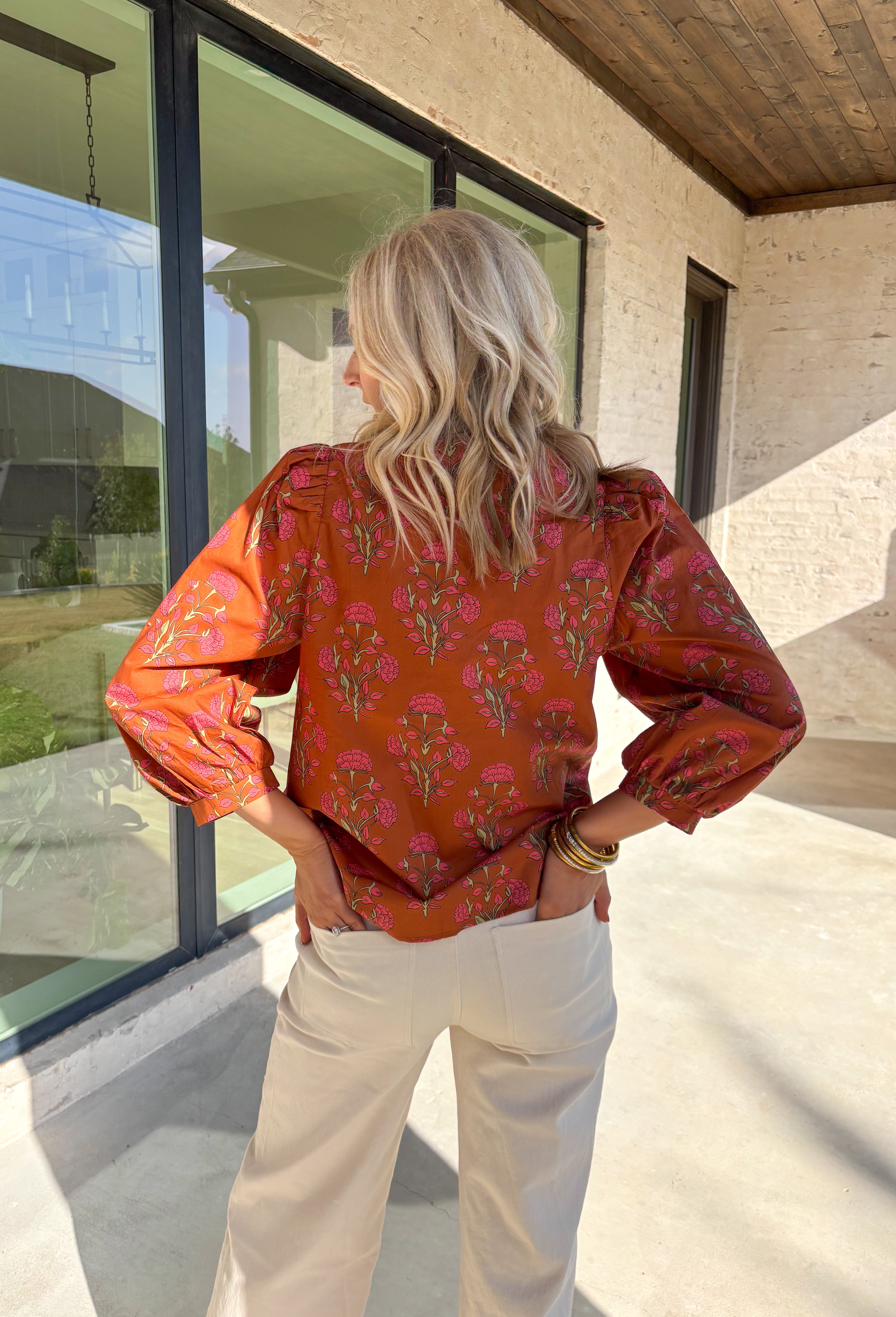 Bring a soft, romantic touch to your winter wardrobe with this floral puff sleeve top by Entro. Designed in a warm brown base with a pink floral print, this top features a contrast embroidered knot trim that outlines the v-neck for an extra hint of detail. The long puff sleeves add a feminine finish, making it perfect for cozy days that still call for a polished look.