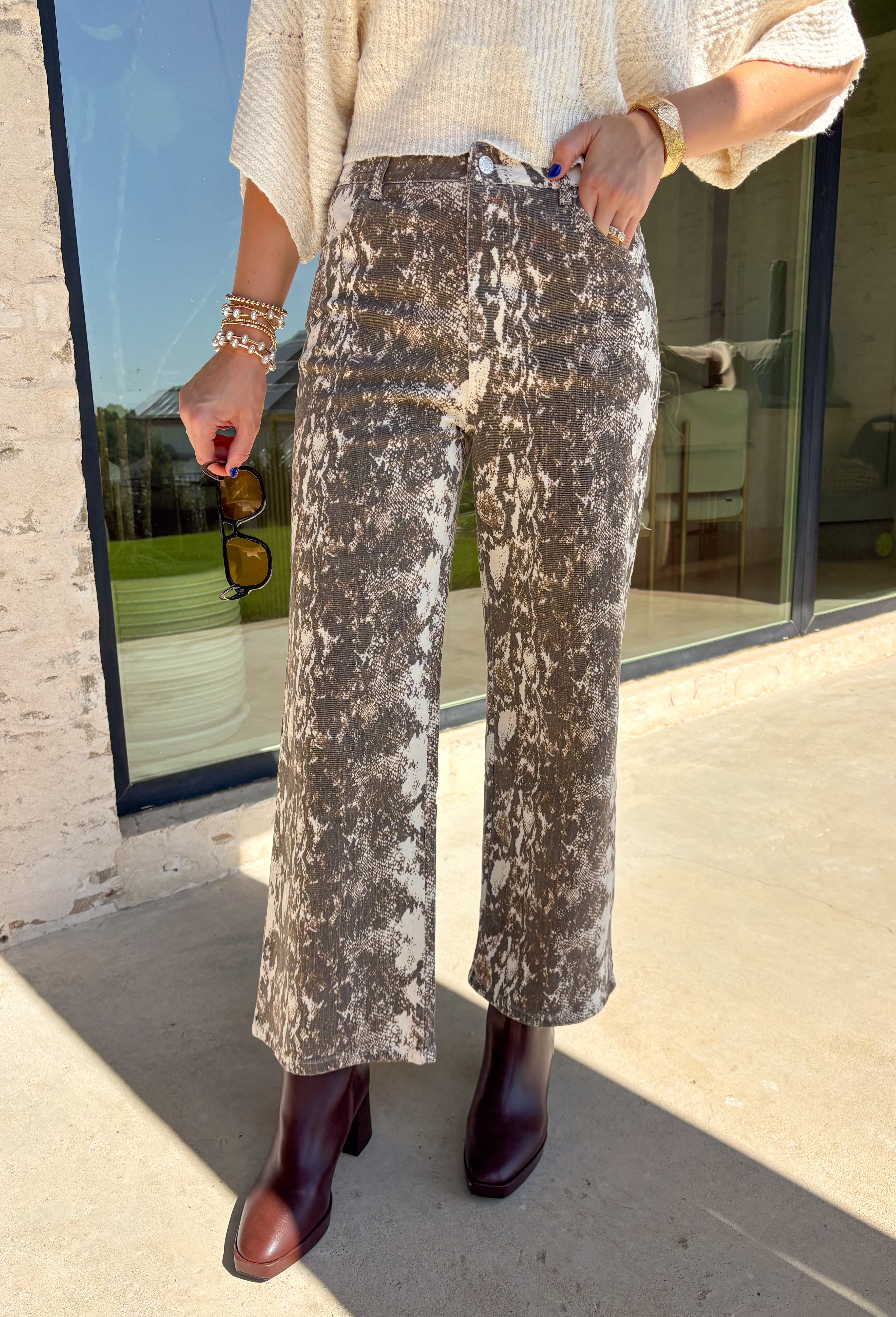 Make a statement with these effortlessly stylish cropped wide leg pants from Entro. Designed in an eye-catching ecru and brown snake print, these versatile pants bring the perfect mix of bold style and everyday comfort. The flattering wide leg silhouette and cropped length create a modern look that's easy to dress up or down, while the classic zip-fly button closure and functional pockets make them as practical as they are chic.