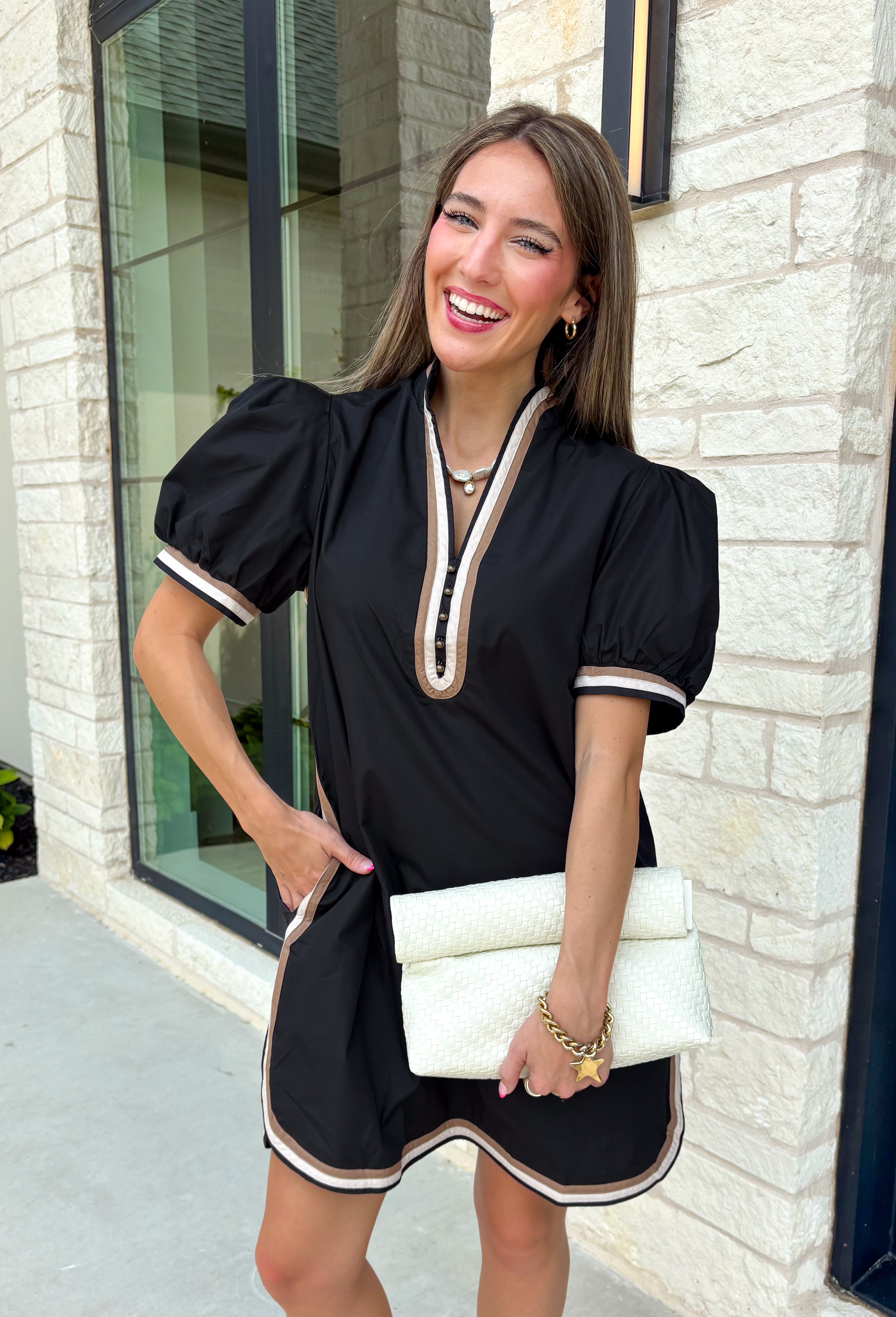 Classic with a modern twist, this black dress is the definition of effortless fall style. Classic black is beautifully accented with tan and cream trim along the front, sides, hem, and sleeves for a look that feels both timeless and eye-catching. The front button details and soft puff sleeves add just the right amount of charm, while the fully lined design and side pockets make it as comfortable as it is stylish. 