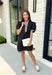 Classic with a modern twist, this black dress is the definition of effortless fall style. Classic black is beautifully accented with tan and cream trim along the front, sides, hem, and sleeves for a look that feels both timeless and eye-catching. The front button details and soft puff sleeves add just the right amount of charm, while the fully lined design and side pockets make it as comfortable as it is stylish. 
