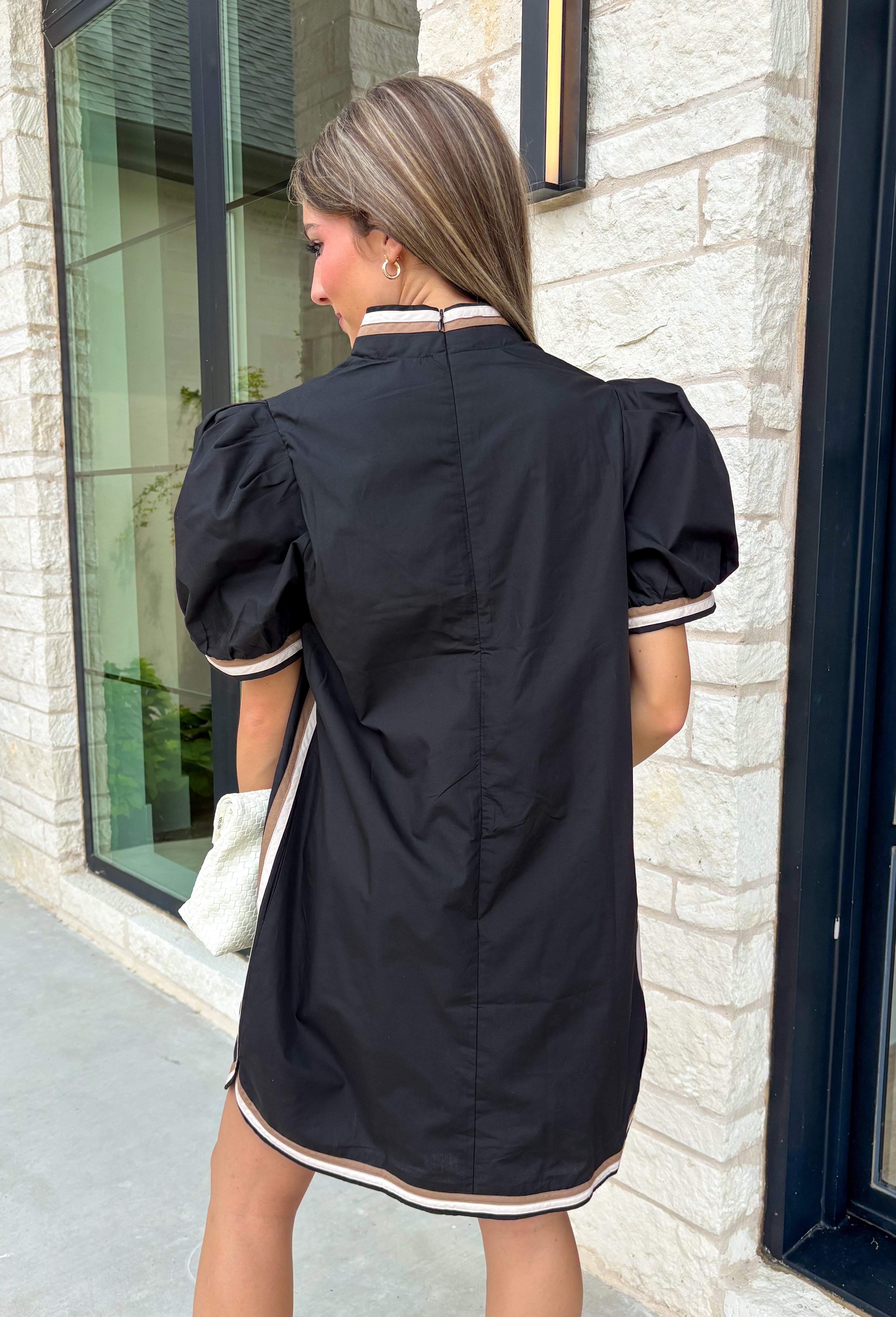 Classic with a modern twist, this black dress is the definition of effortless fall style. Classic black is beautifully accented with tan and cream trim along the front, sides, hem, and sleeves for a look that feels both timeless and eye-catching. The front button details and soft puff sleeves add just the right amount of charm, while the fully lined design and side pockets make it as comfortable as it is stylish. 