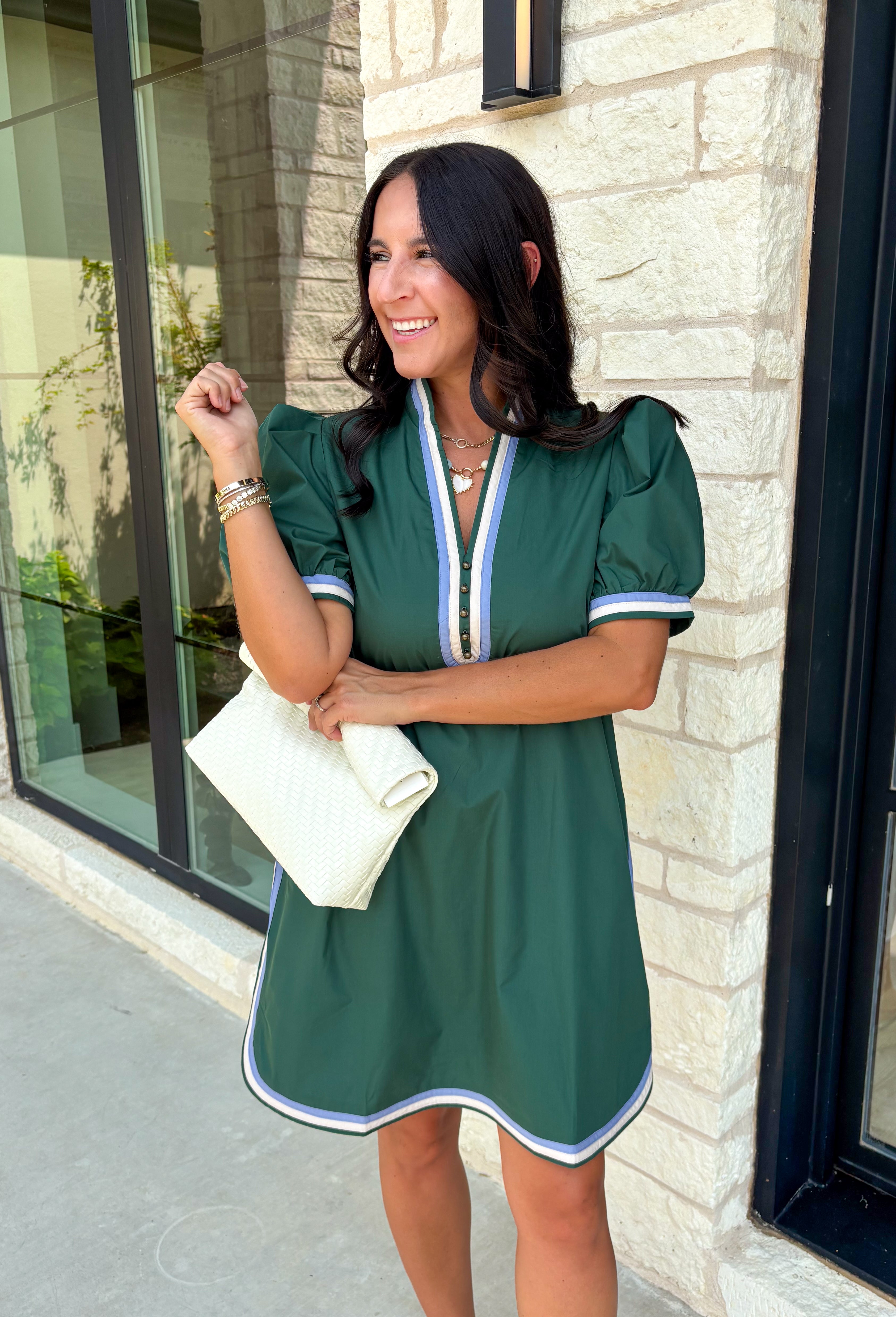 Classic with a modern twist, this hunter green dress is the definition of effortless fall style. Rich hunter green is beautifully accented with light blue and white trim along the front, sides, hem, and sleeves for a look that feels both timeless and eye-catching. The front button details and soft puff sleeves add just the right amount of charm, while the fully lined design and side pockets make it as comfortable as it is stylish. 