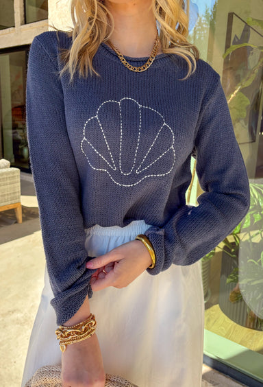 This navy lightweight knit sweater is giving effortless coastal vibes in the cutest way! Featuring a white seashell embroidered print across the front, it adds the perfect playful detail without being too loud. The soft knit feel makes it easy to toss on for breezy spring days, chilly beach nights, or those mornings when it’s warm in the sun but cool in the shade.