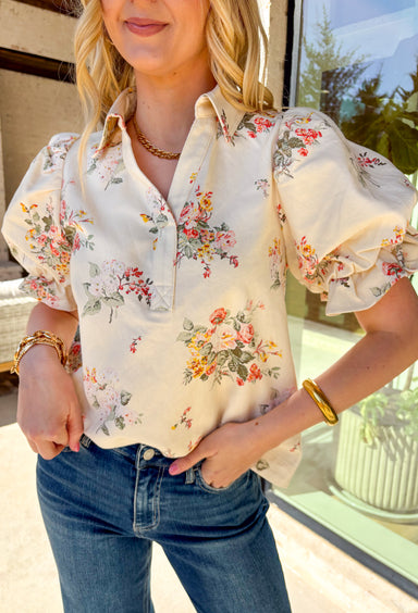 Fresh, playful, and full of spring charm, this off-white short sleeve top by Entro is an easy standout. Designed with a soft, denim-like cotton feel, it features a colorful floral print that brings the perfect pop of seasonal color. The collared neckline keeps it polished, while the statement sleeves with adjustable tie details add a fun, feminine twist. This top is equal parts effortless and eye-catching—perfect for dressing up denim or keeping things casual all spring long.