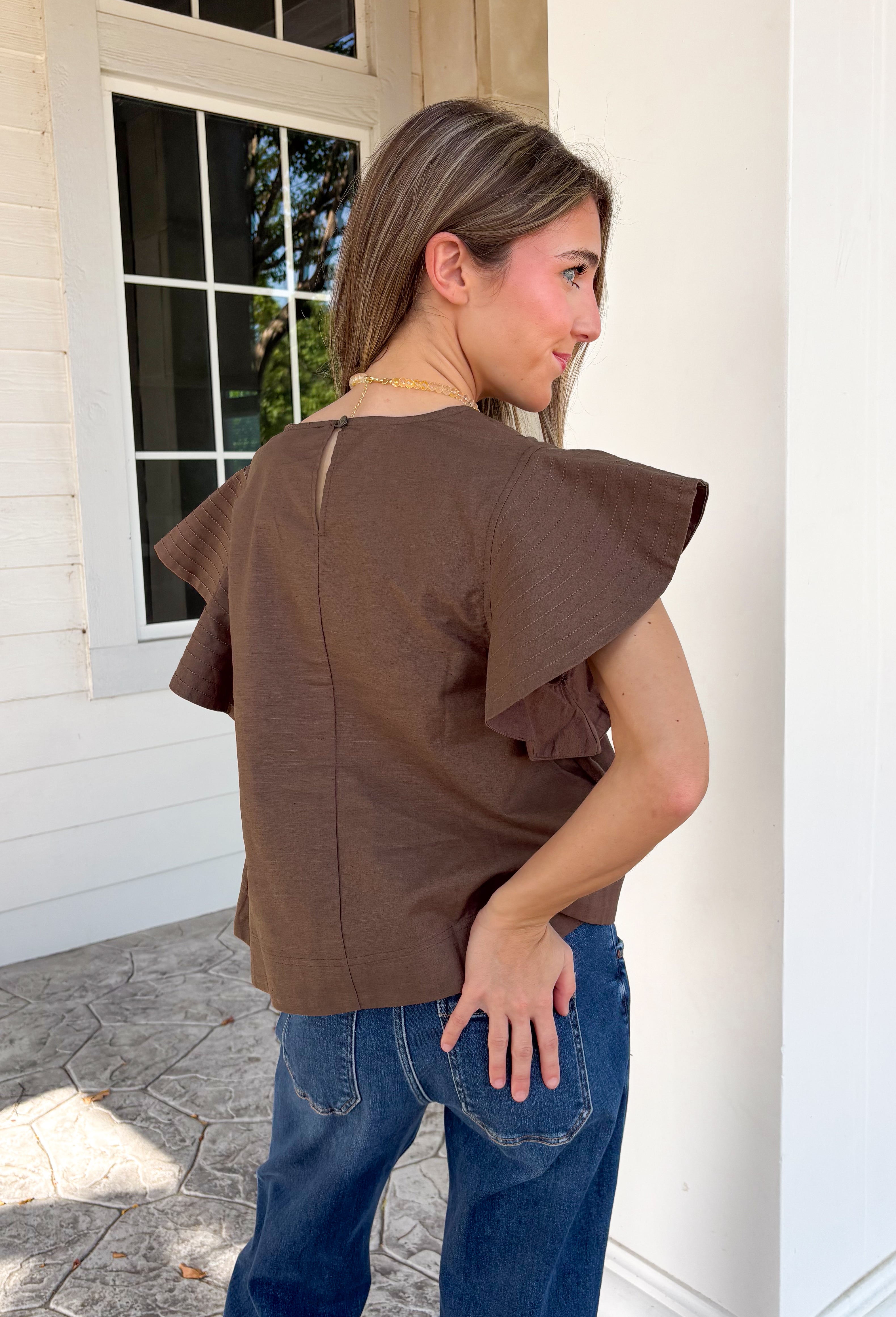 Simple details make all the difference in this effortlessly beautiful brown top! Crafted from a breathable cotton and linen blend, this timeless top is perfect for transitioning through the fall season. The flattering v-neckline is accented with delicate stitch detailing, while flutter sleeves add a soft, feminine touch. A button closure at the back completes the look with subtle charm. 